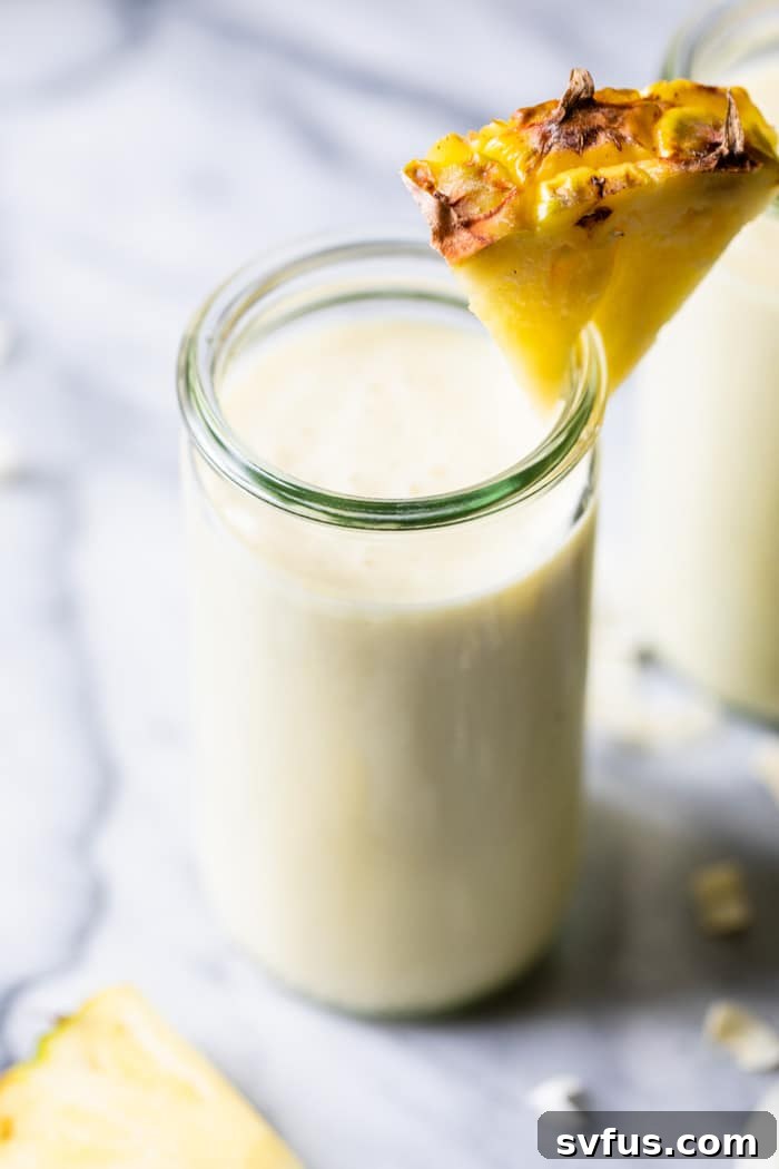 A beautifully garnished Piña Colada Smoothie in a glass, with a pineapple wedge, ready to be enjoyed as a healthy and refreshing treat.