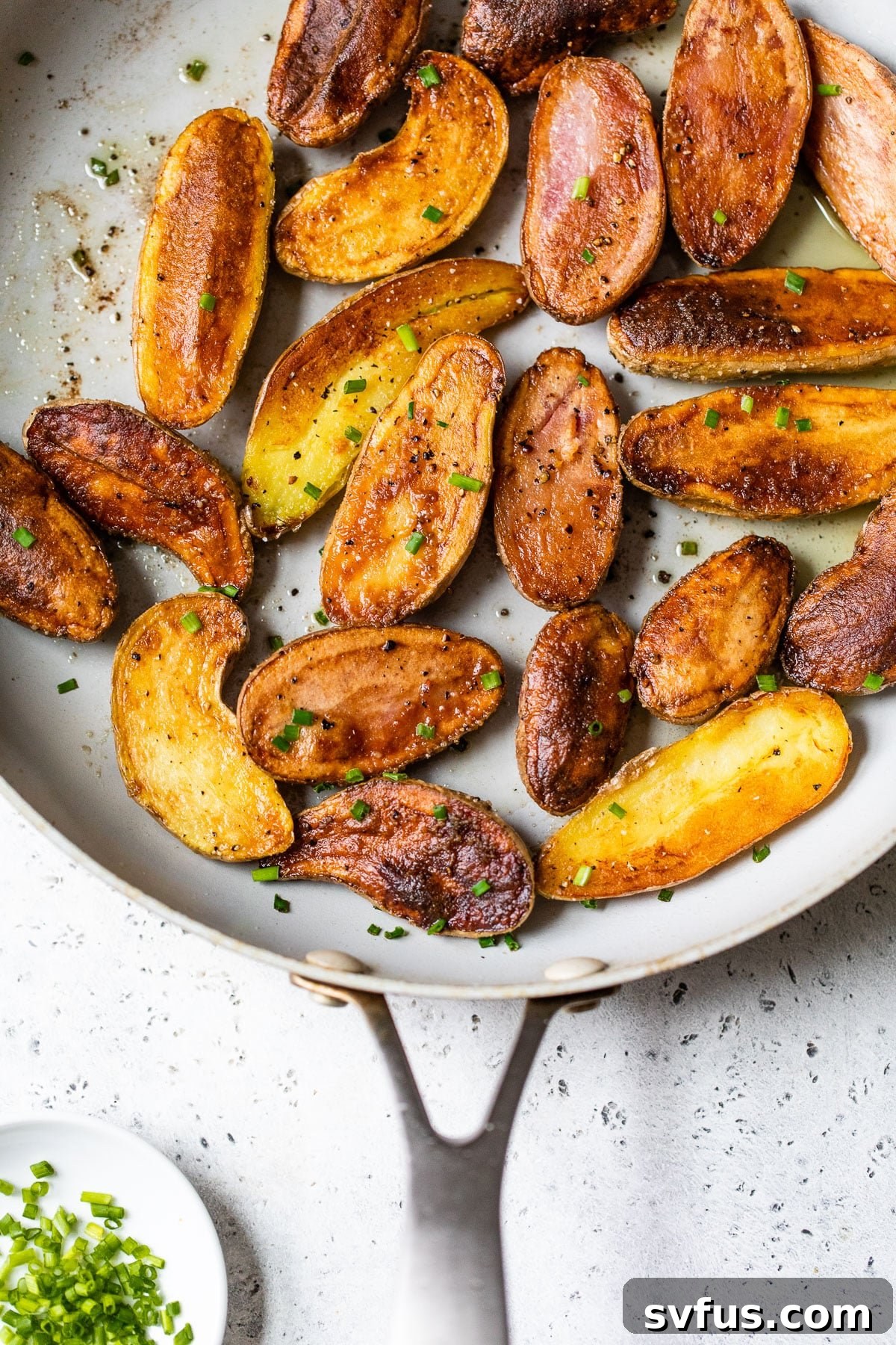 crispy roasted fingerling potatoes in a cast iron skillet, garnished with fresh herbs