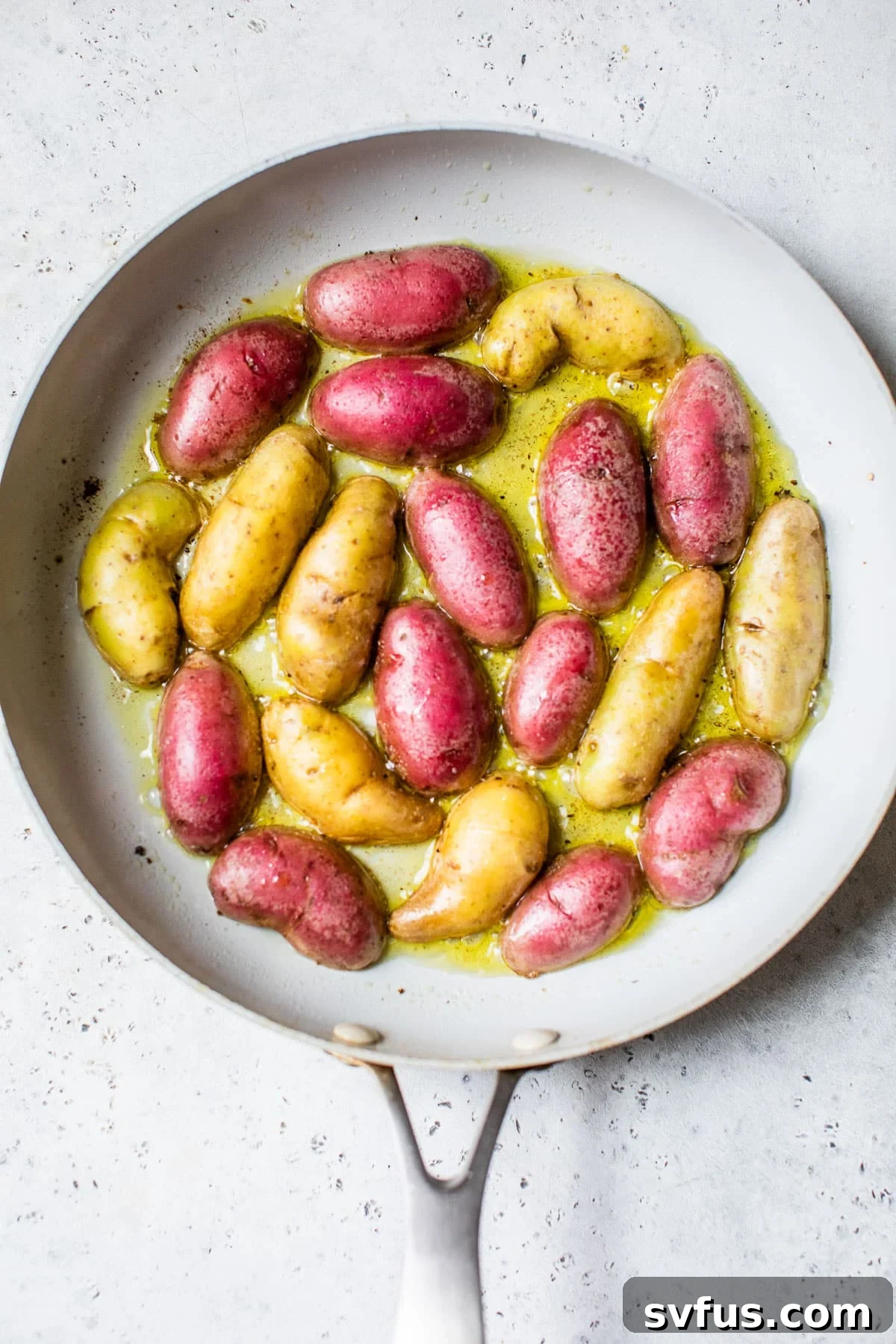 sliced fingerling potatoes cooking cut-side down in olive oil in a hot cast iron skillet