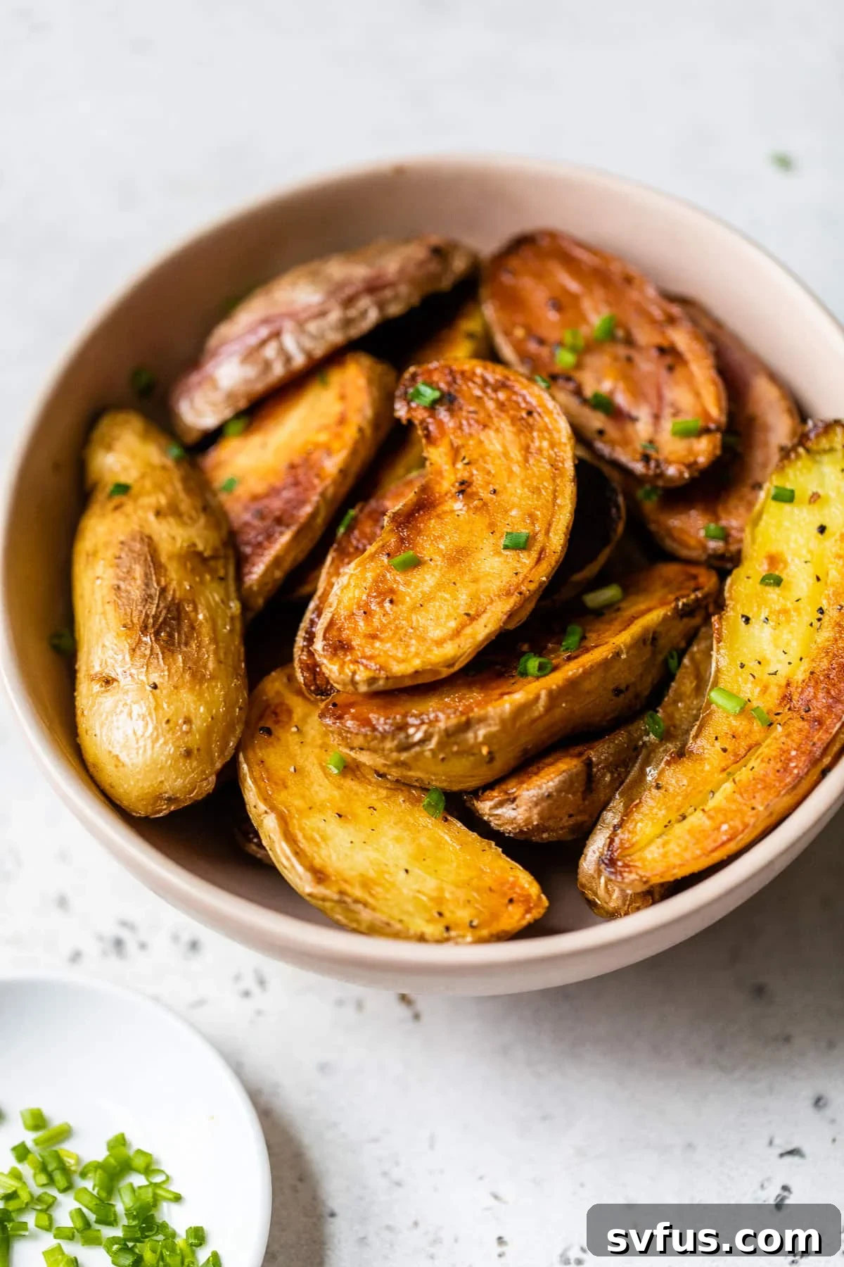 roasted fingerling potatoes in a serving bowl, garnished with fresh herbs