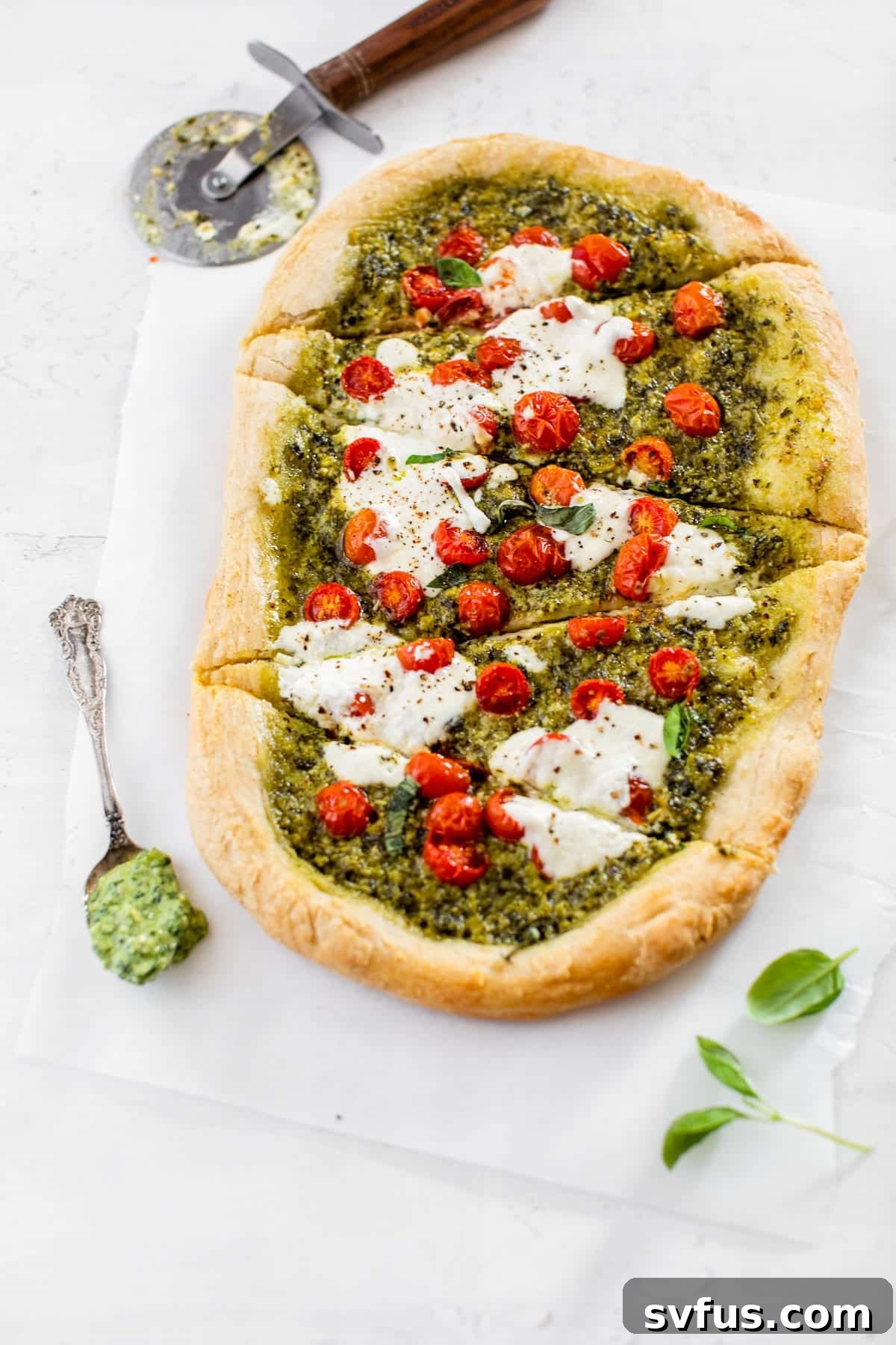 Several slices of Kale Pesto Pizza on parchment paper, highlighting the rich colors and textures and inviting a taste.