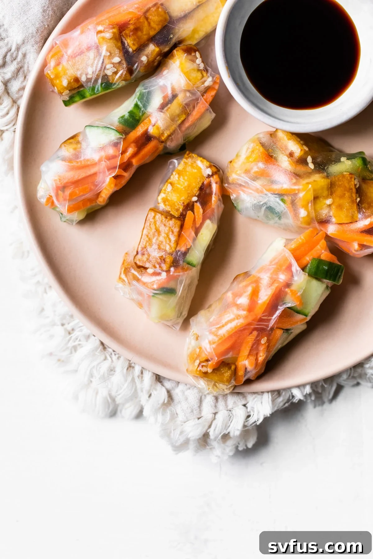 Freshly made sesame tofu spring rolls arranged artfully on a white plate, showcasing their vibrant fillings and inviting appearance, ready for dipping.