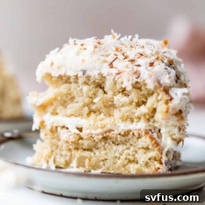 a slice of cake on a plate topped with white icing and shredded coconut