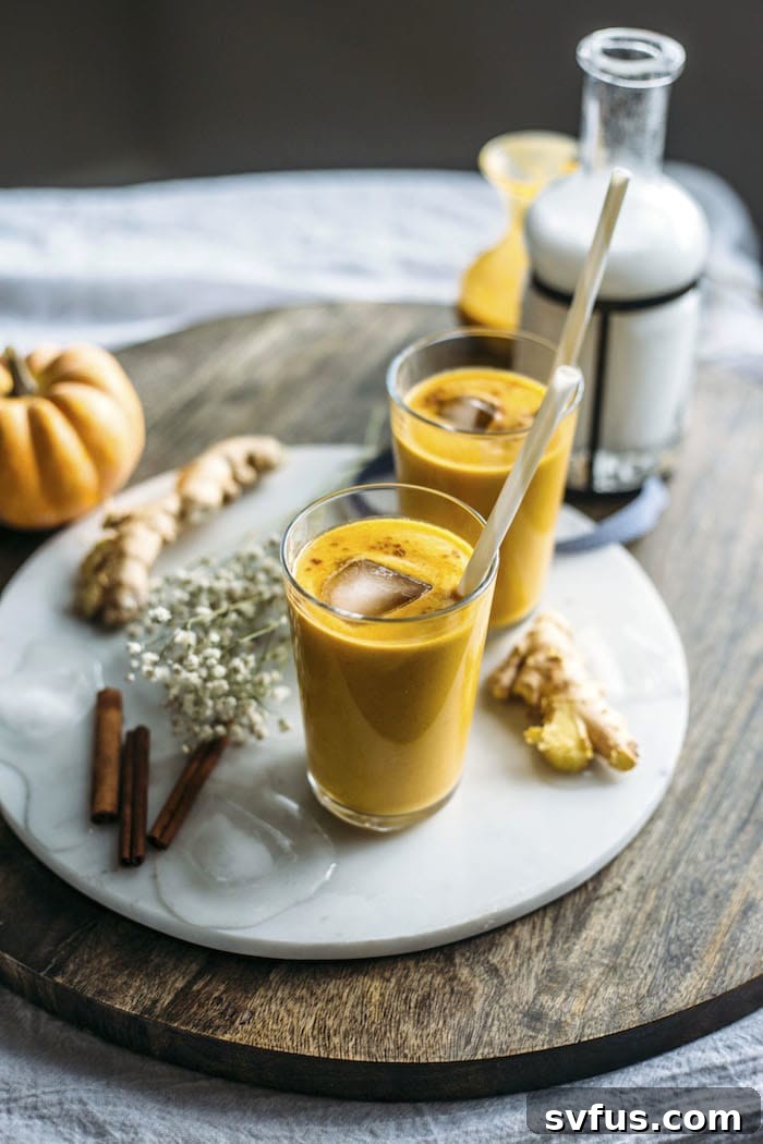 Two glasses of Ginger Pumpkin Smoothie on a wooden table, emphasizing a healthy fall beverage choice.