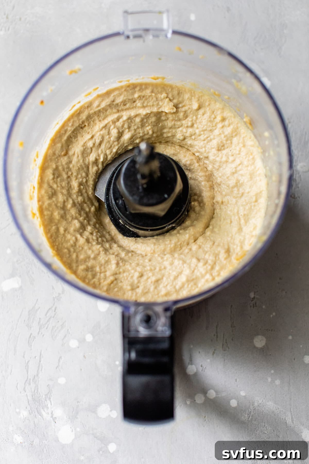 Creamy homemade hummus being processed in a food processor, showing its smooth consistency.
