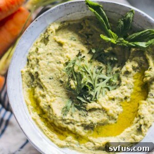 pesto hummus in a bowl topped with fresh basil