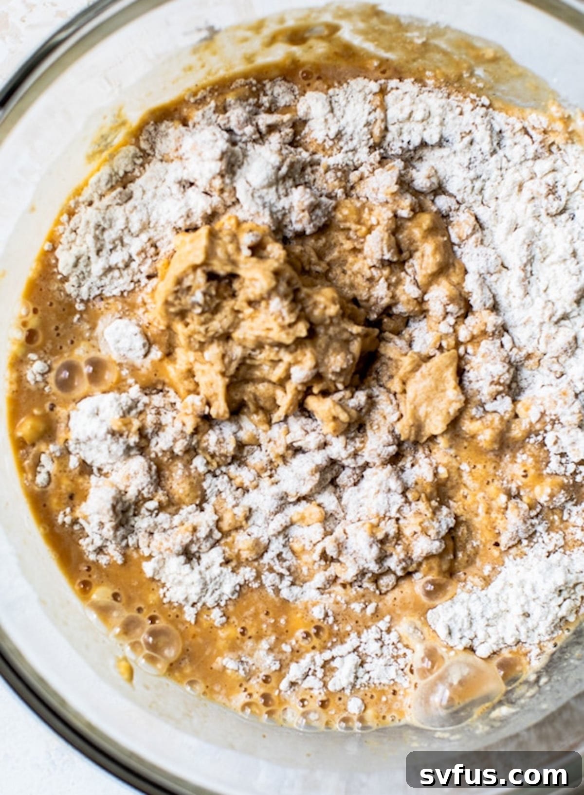 Close-up shot of creamy vegan pumpkin cake batter in a mixing bowl, ready to be poured into pans.
