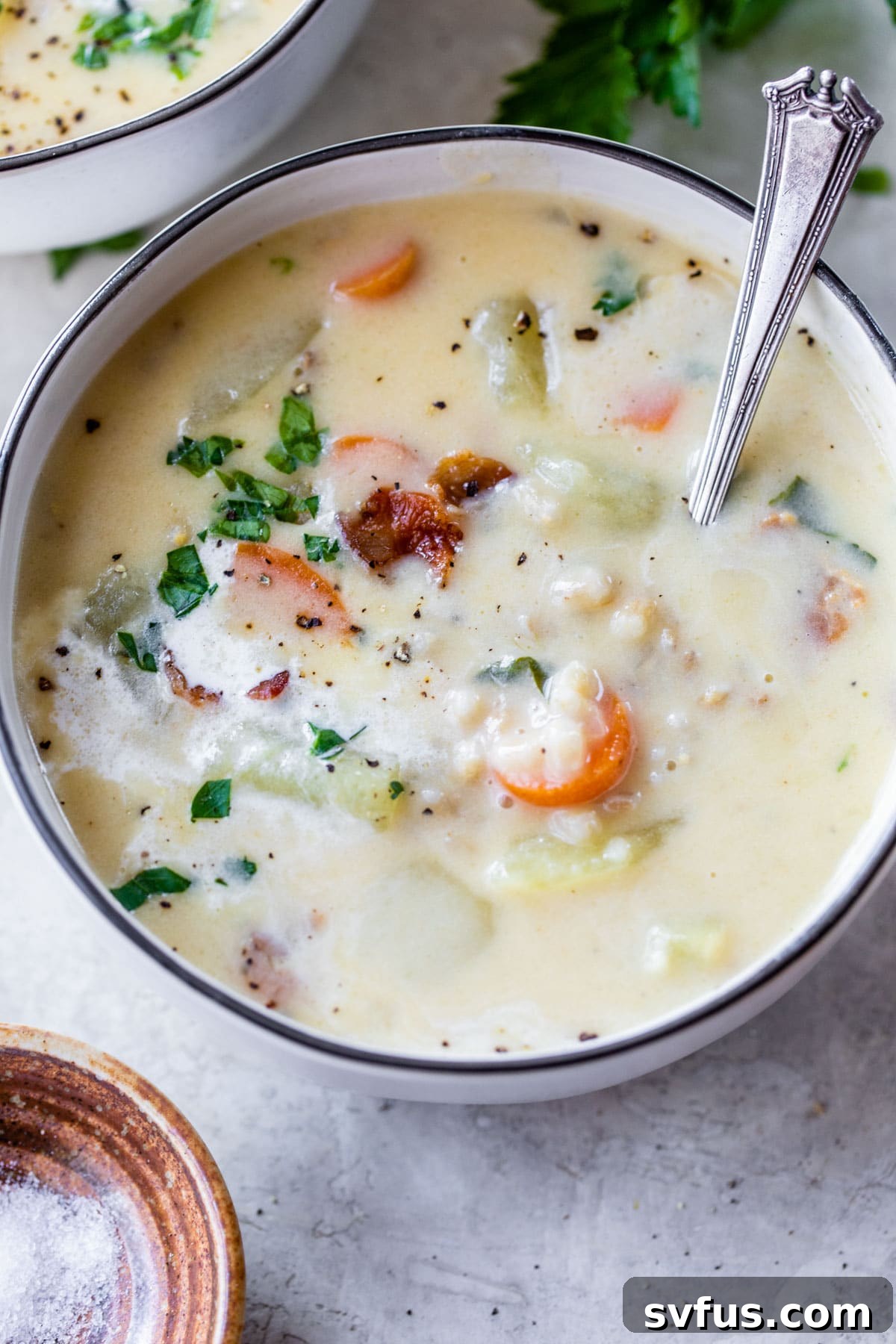 A simple yet elegant shot of a creamy soup in a bowl, with a spoon resting inside, highlighting its inviting texture.