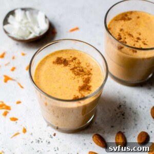 Carrot Cake Smoothie in a glass, garnished with shredded coconut and almonds