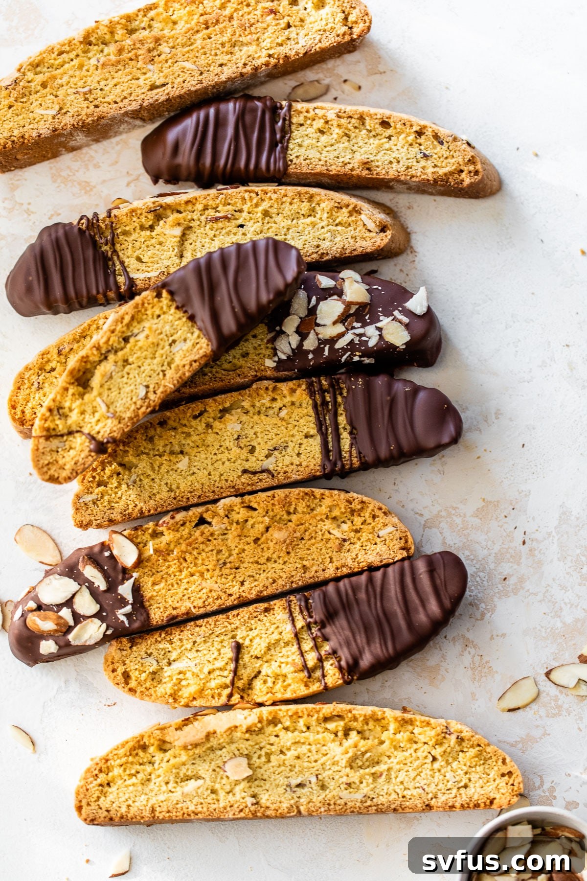 Crisp almond biscotti, elegantly dipped in dark chocolate and topped with sliced almonds, ready for dunking in coffee.