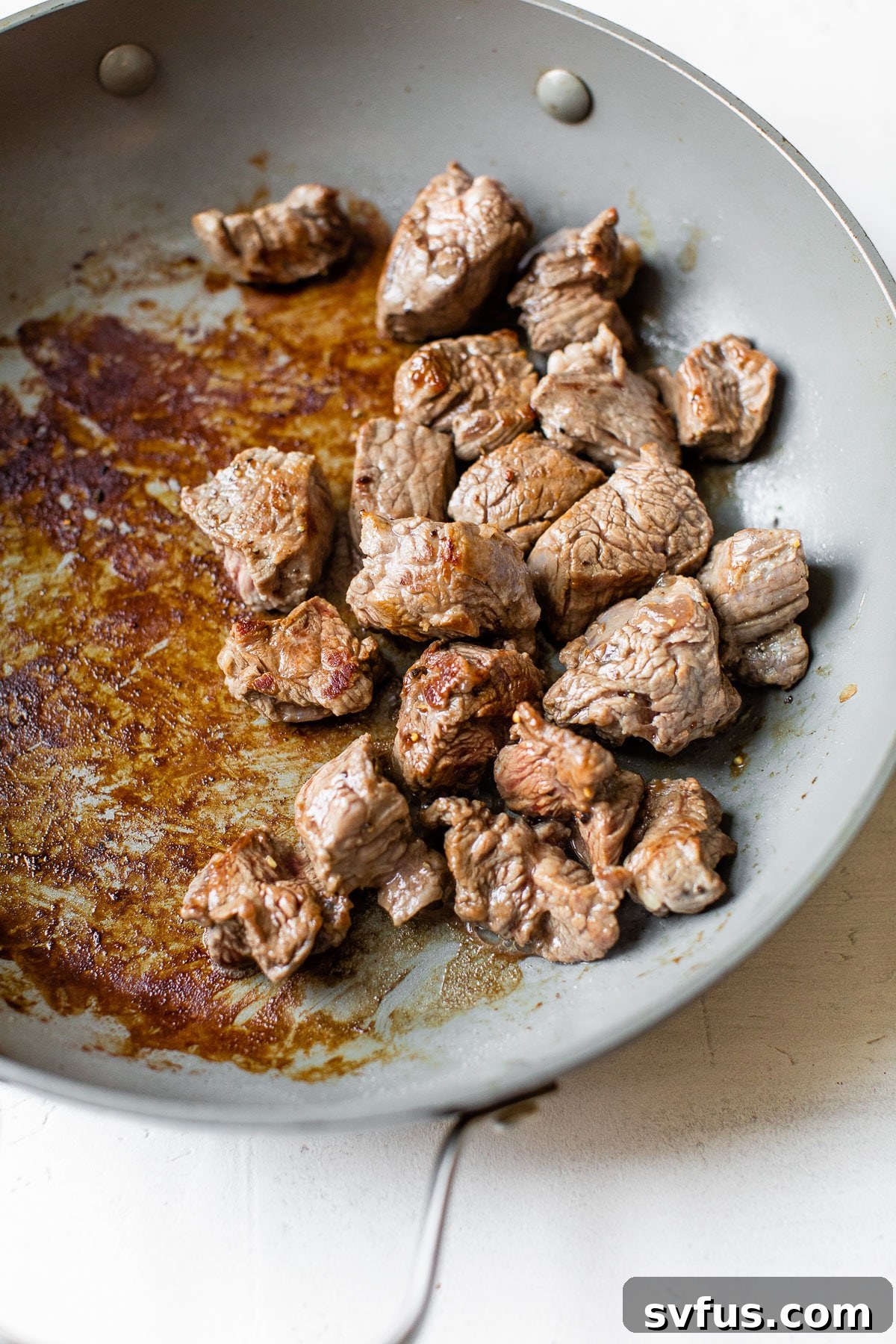 Thinly sliced beef, seasoned with salt and pepper, being pan-seared in a skillet to tender perfection.