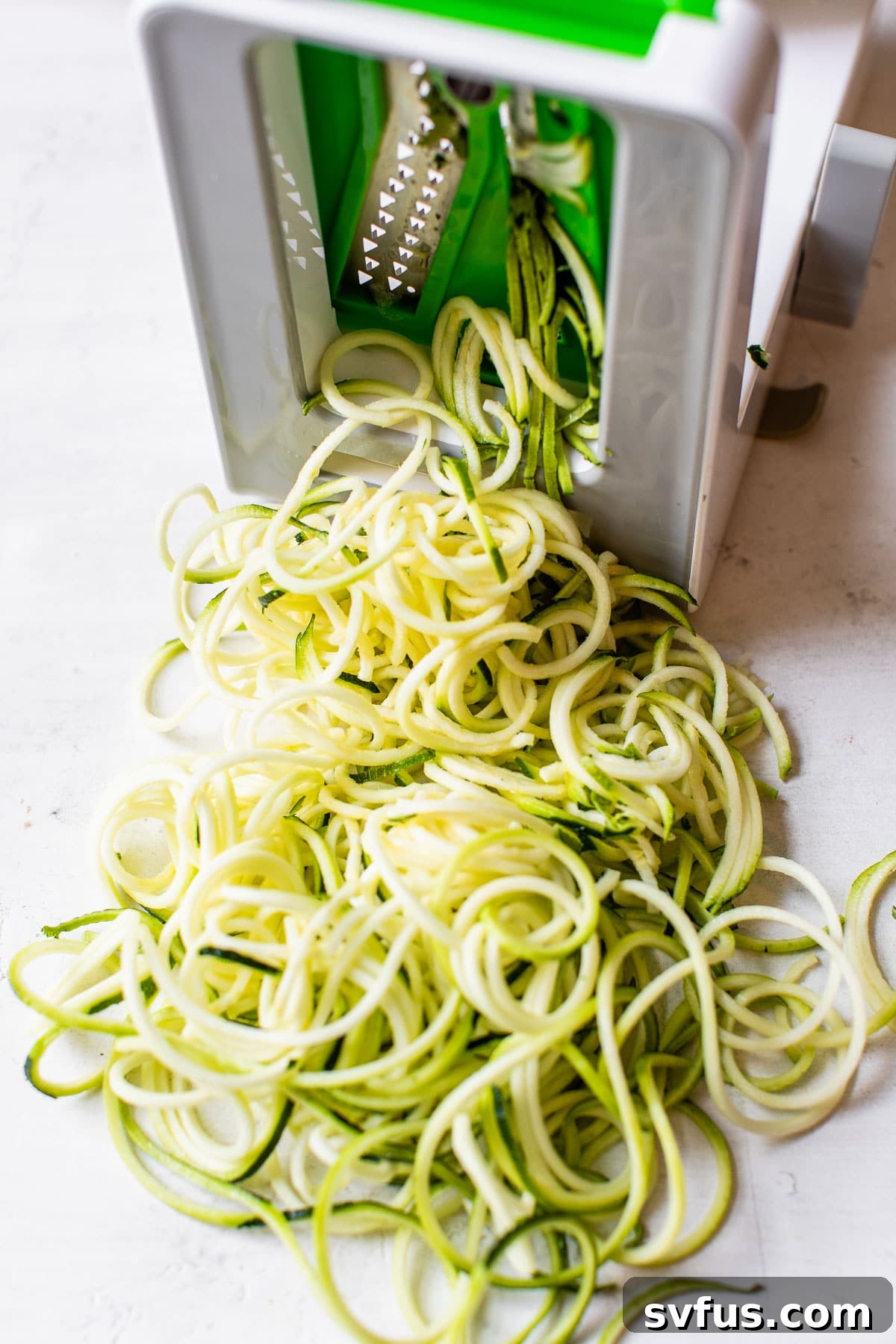 Fresh zucchini being spiralized into long, healthy noodles, ready to be added to the pho.