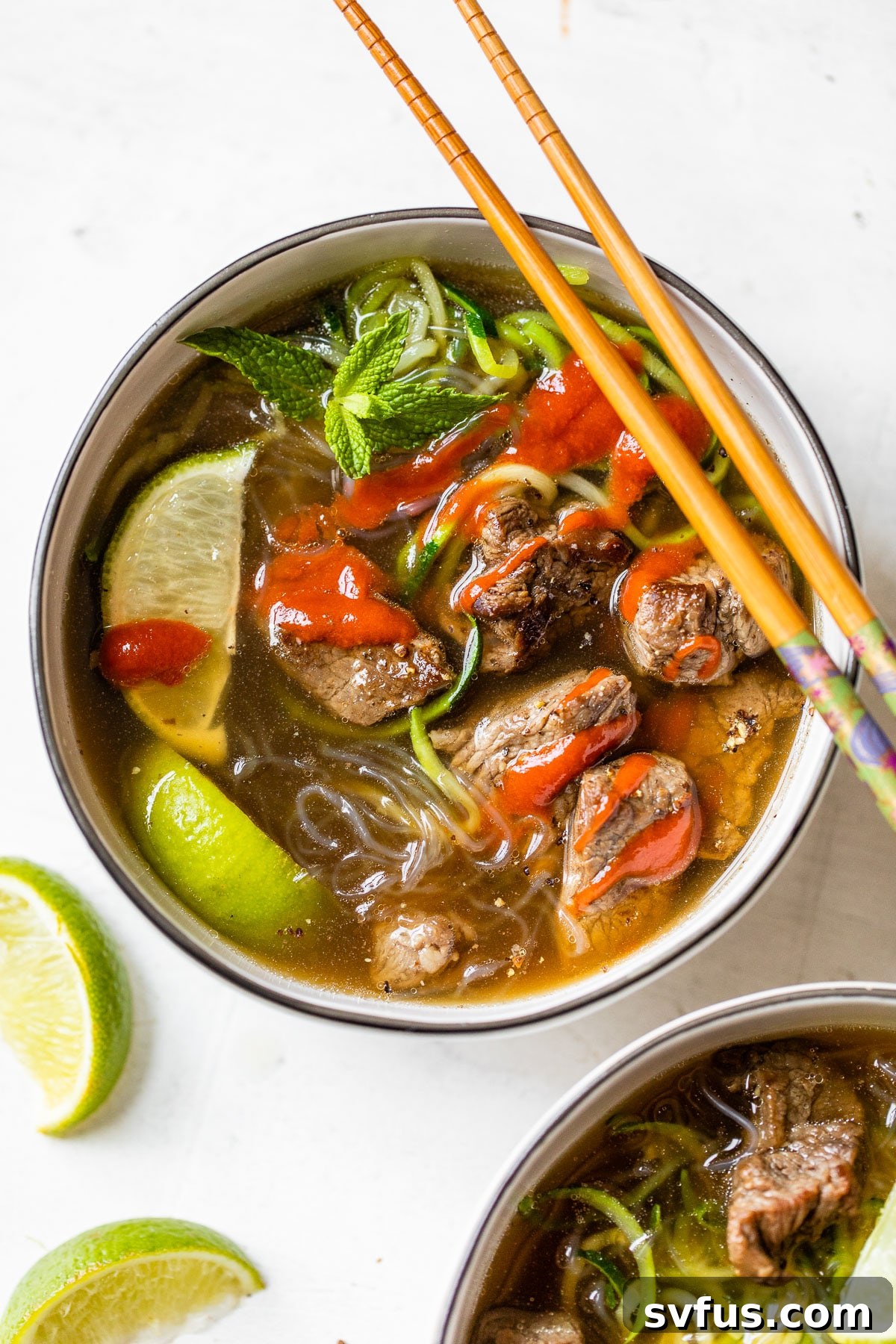 A beautifully presented bowl of Paleo Beef Pho, adorned with fresh herbs, tender beef, and lime wedges, showcasing its vibrant appeal.