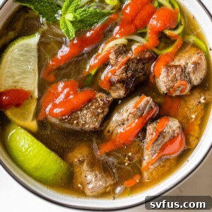 bowl of soup with beef topped with sriracha