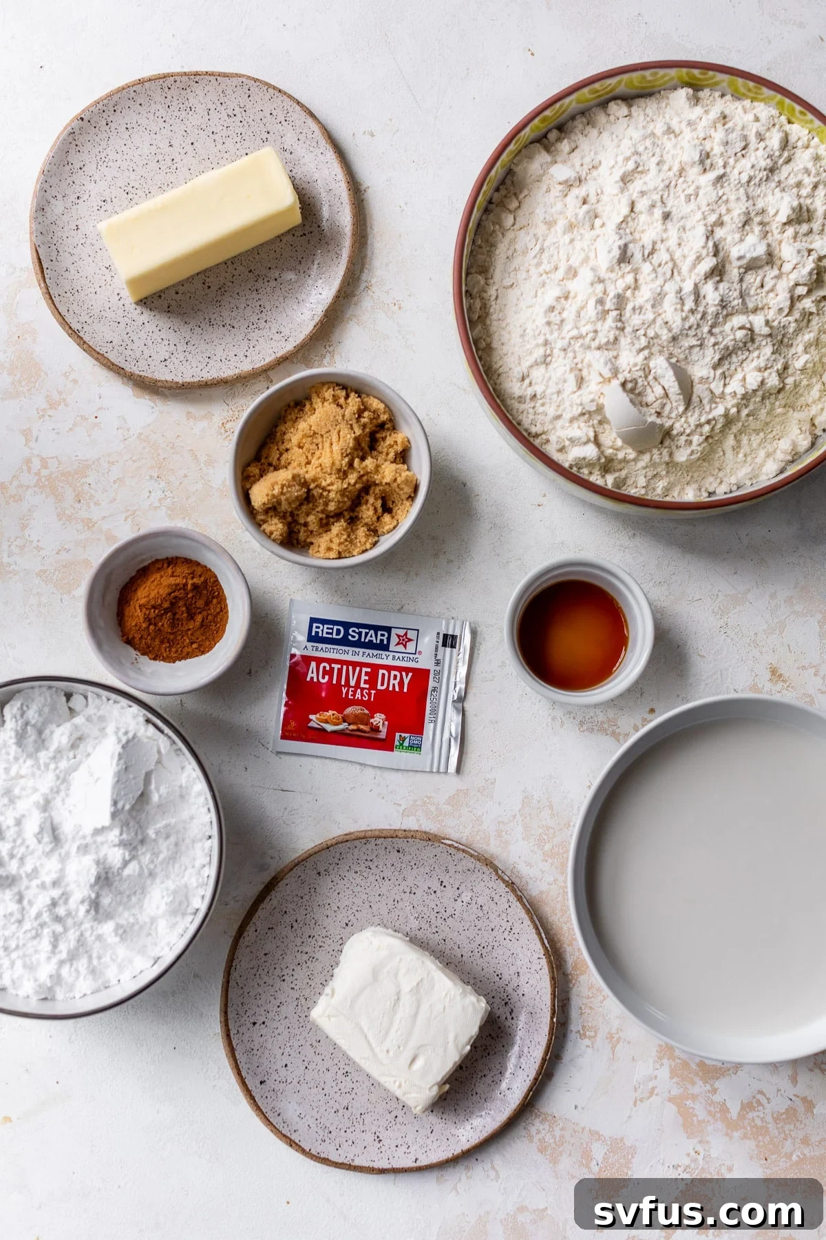 Overhead view of the individual ingredients for vegan cinnamon rolls laid out in separate bowls, ready for baking.