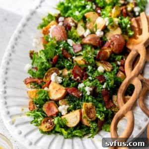 wooden salad tongs next to a potato brussels sprouts salad on a large white platter.