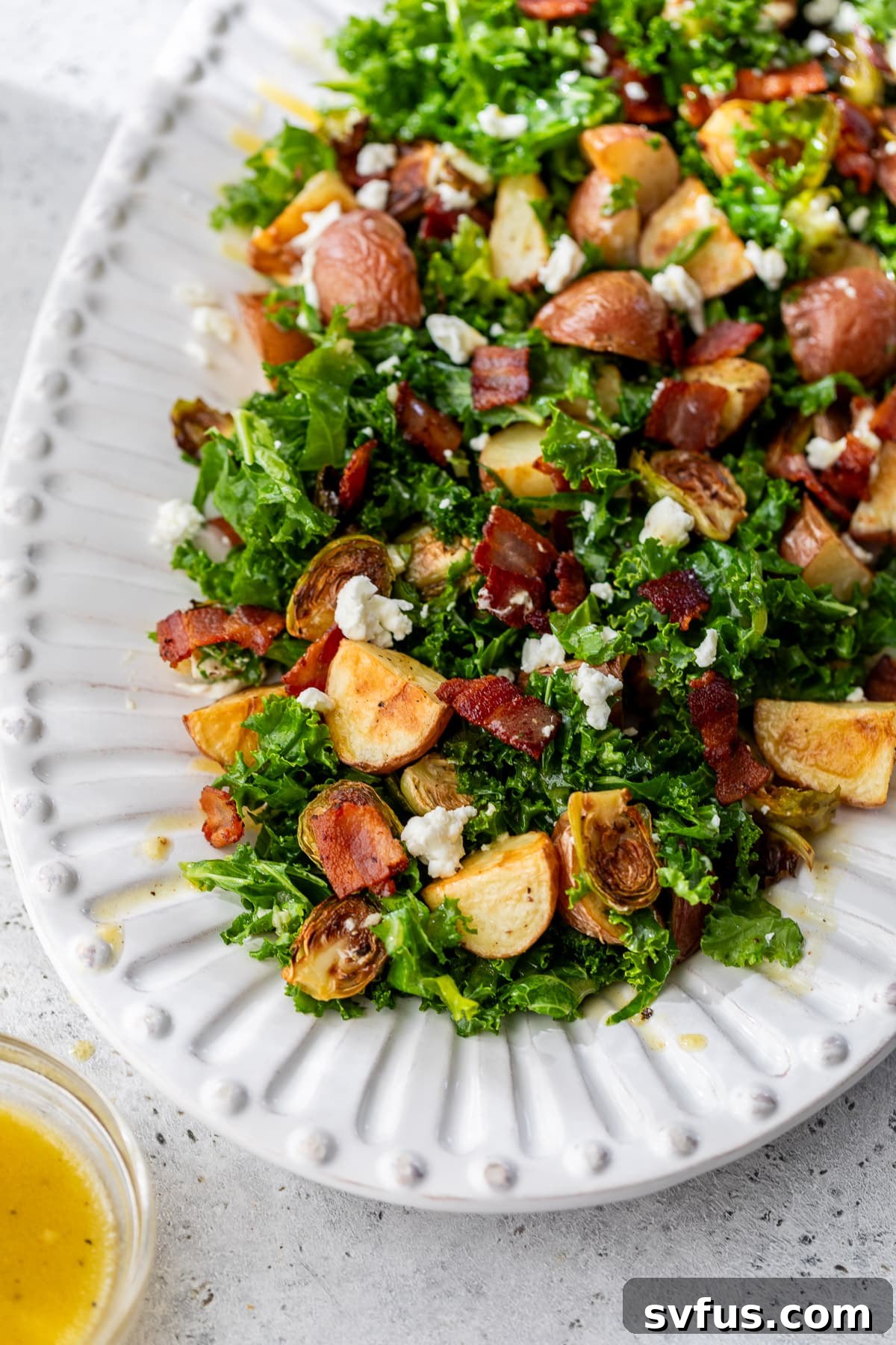 A large white platter presenting a beautifully arranged Potato Brussels Sprouts Salad, garnished and ready to be served.
