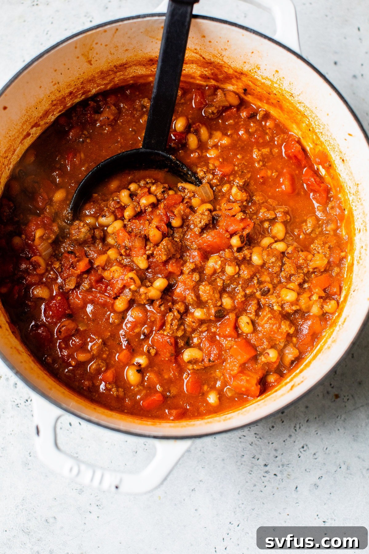 A large Dutch oven filled with rich, bubbling Black Eyed Peas Beer Chili, showcasing its hearty texture.