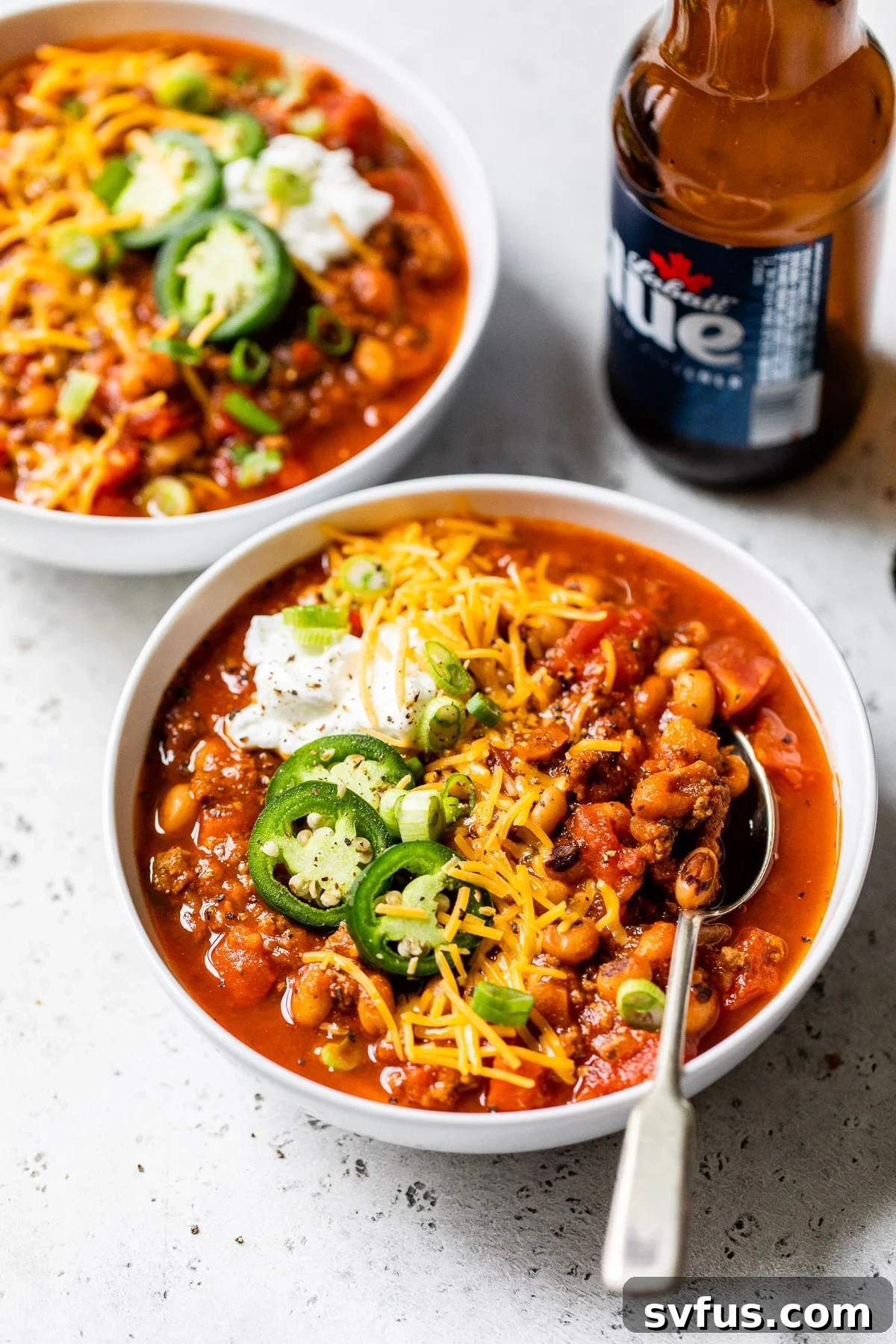 A bowl of Black Eyed Peas Beer Chili placed next to a bottle of beer, highlighting the key ingredient.