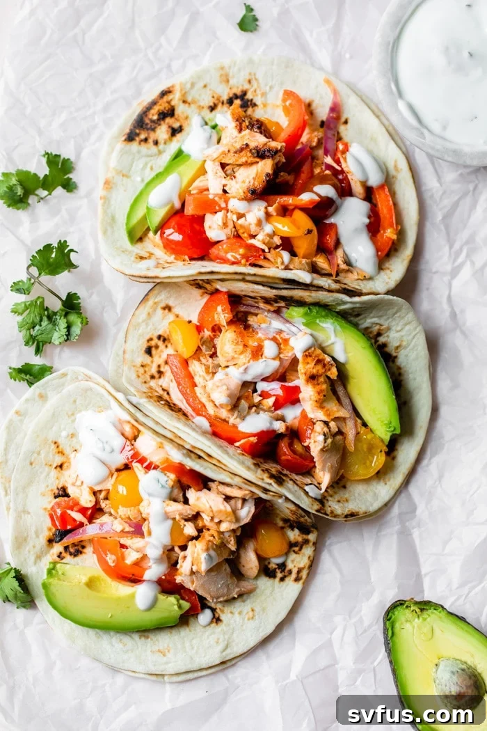salmon fajitas on parchment paper with a side of avocado, lime, and sauce