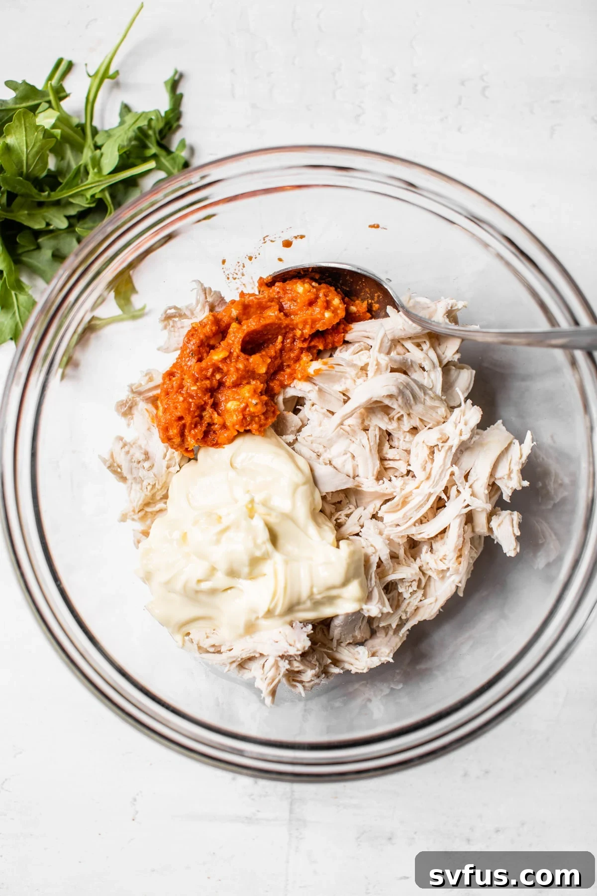 Chicken, mayonnaise, and pesto in a mixing bowl