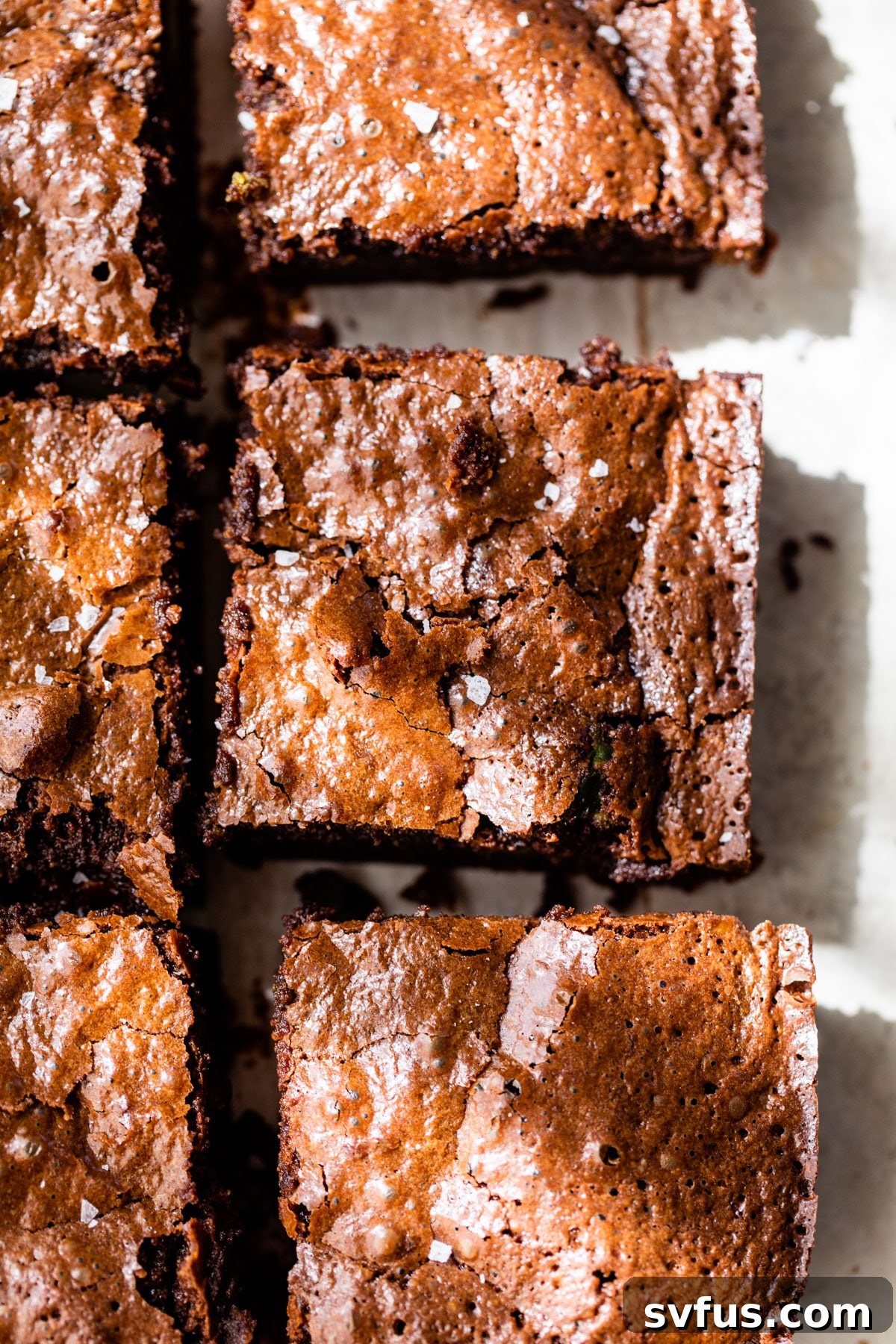 Close-up of freshly baked avocado brownies, showcasing their irresistible crackly tops and a sprinkle of sea salt.