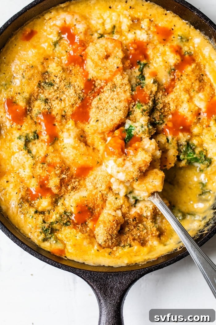 A vibrant, close-up shot of a cast-iron skillet filled with bubbling cheesy cauliflower rice and perfectly cooked shrimp, garnished with golden-brown breadcrumbs.
