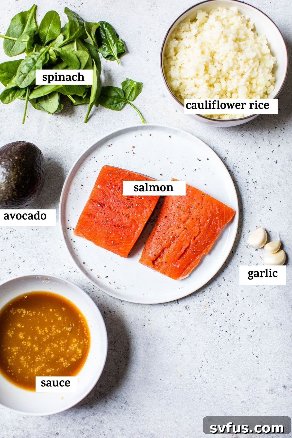 Bowls of raw ingredients including salmon fillets, sliced avocado, fresh spinach, and small bowls of teriyaki sauce ingredients, neatly arranged on a wooden board