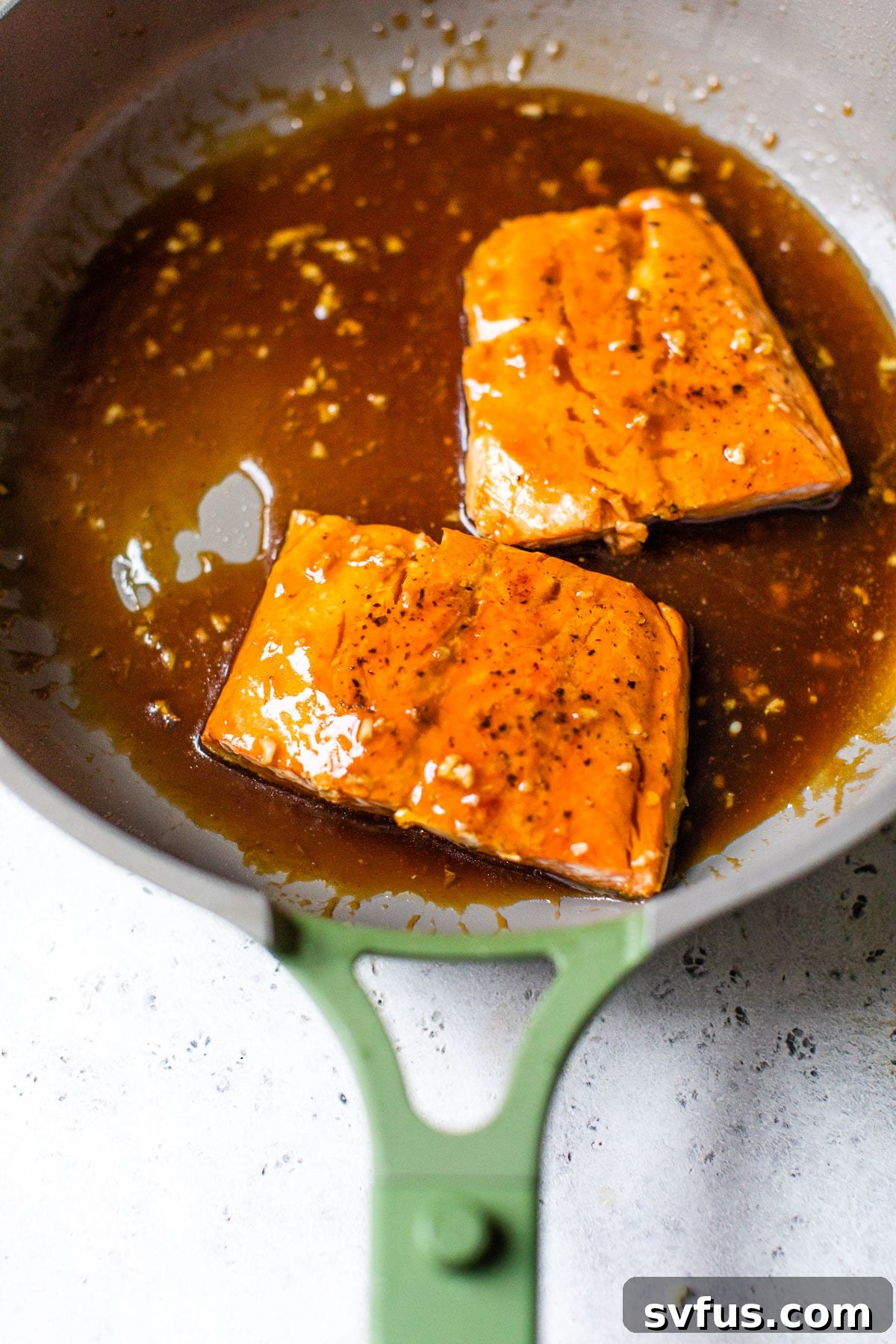 Delicious cooked salmon fillets glistening with thick teriyaki sauce in a skillet, ready to be served