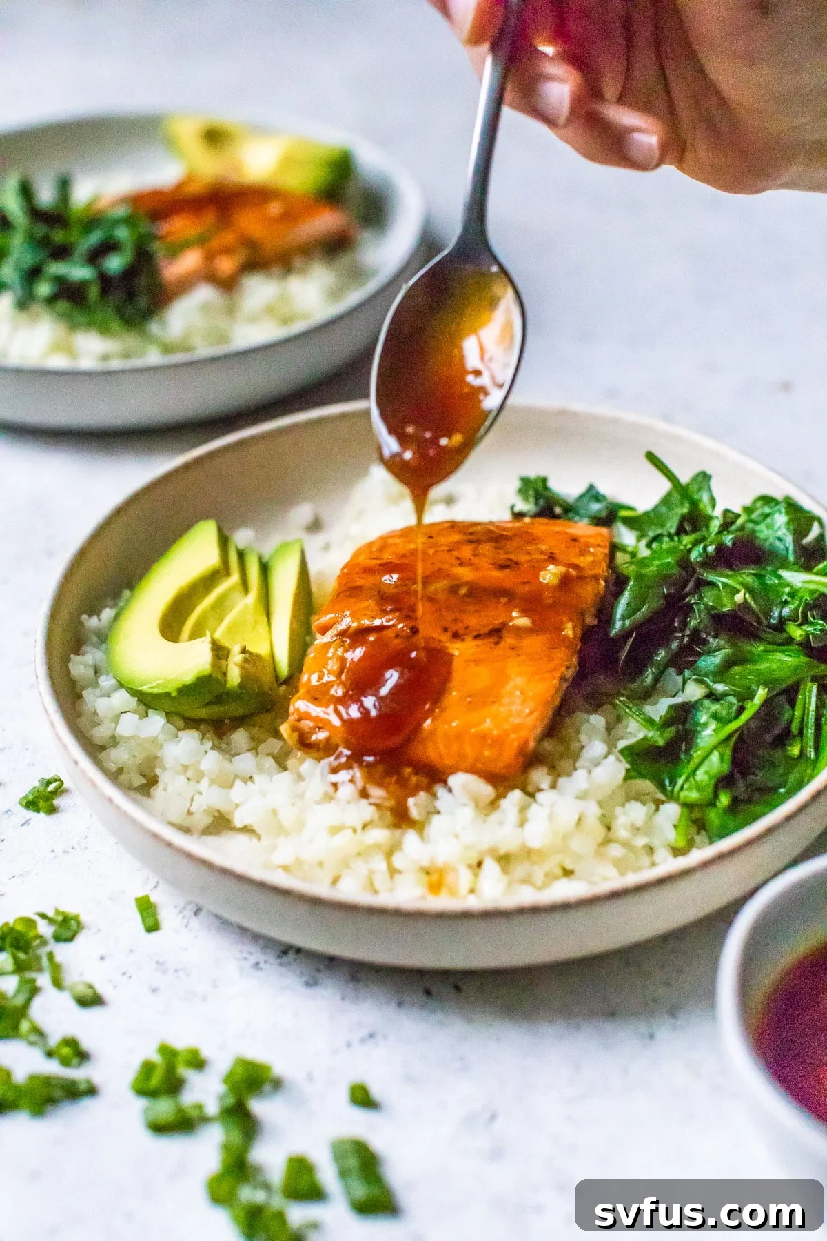Someone artistically drizzling homemade teriyaki sauce over a perfectly seared salmon fillet in a bowl