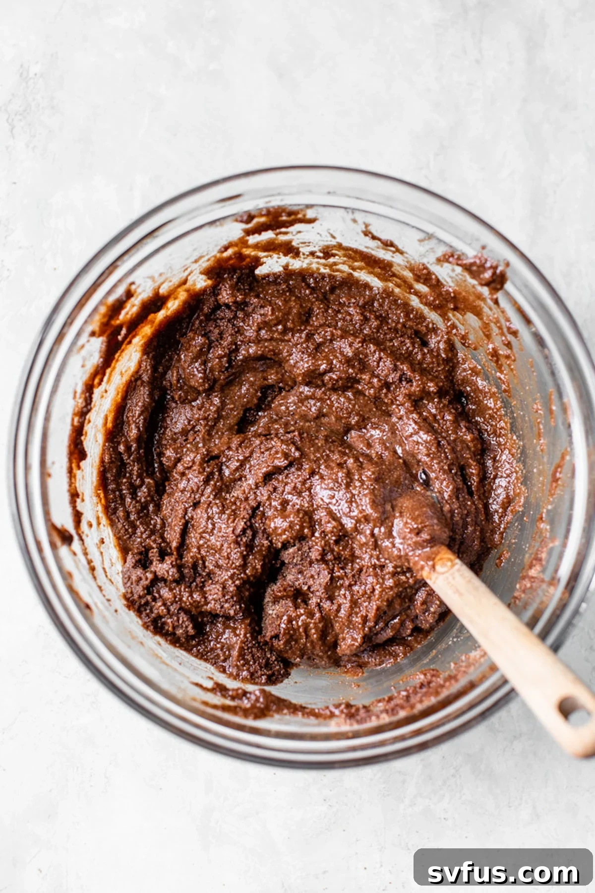 Smooth chocolate cake batter in a clear glass mixing bowl.