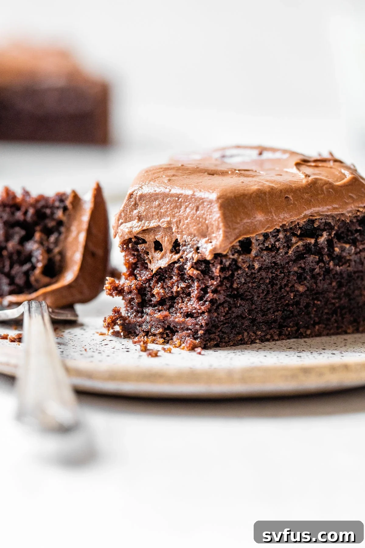 A slice of almond flour chocolate cake with a bite taken out, showing the moist interior.