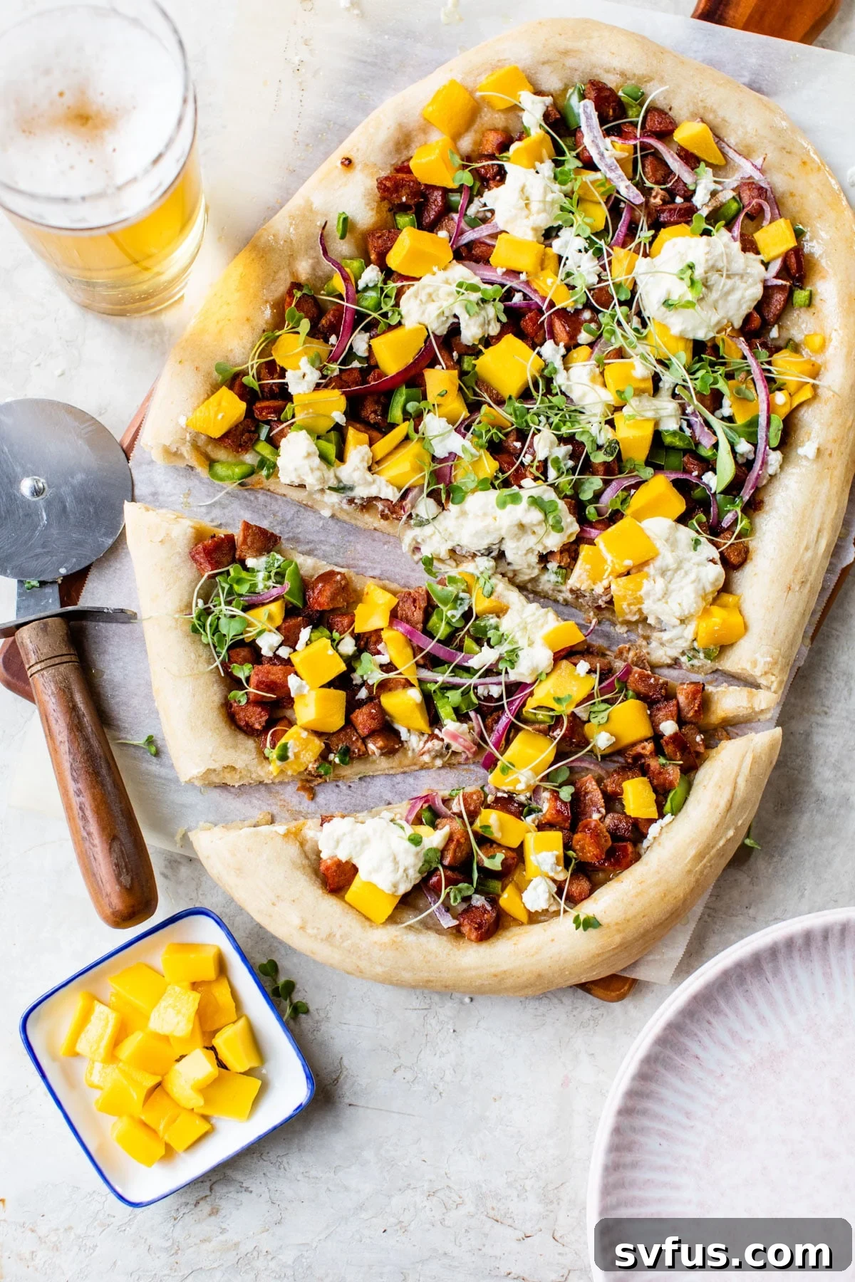 A delicious Chorizo Mango Pizza expertly cut into perfect slices, showcasing the rich chorizo, sweet mango chunks, and decadent melted burrata and goat cheese.