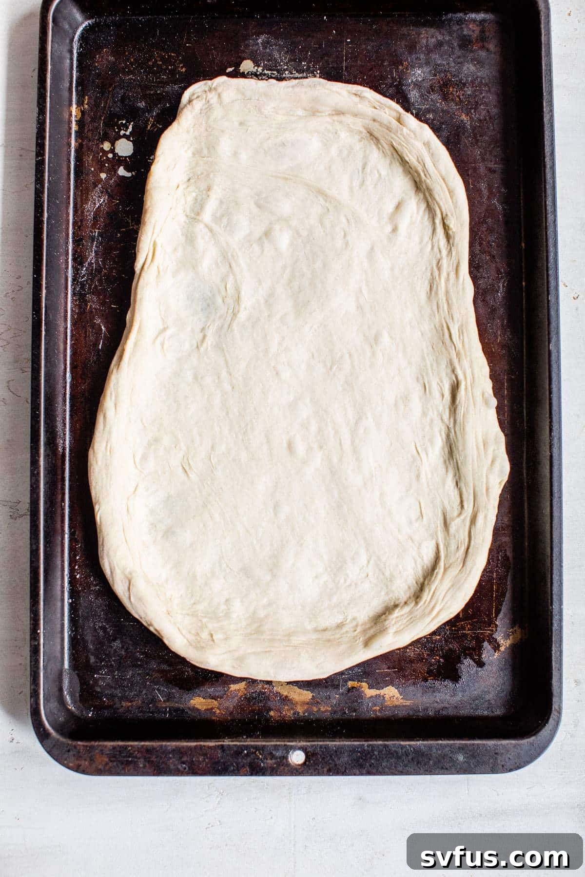 Pizza dough baking on a baking sheet, becoming golden brown