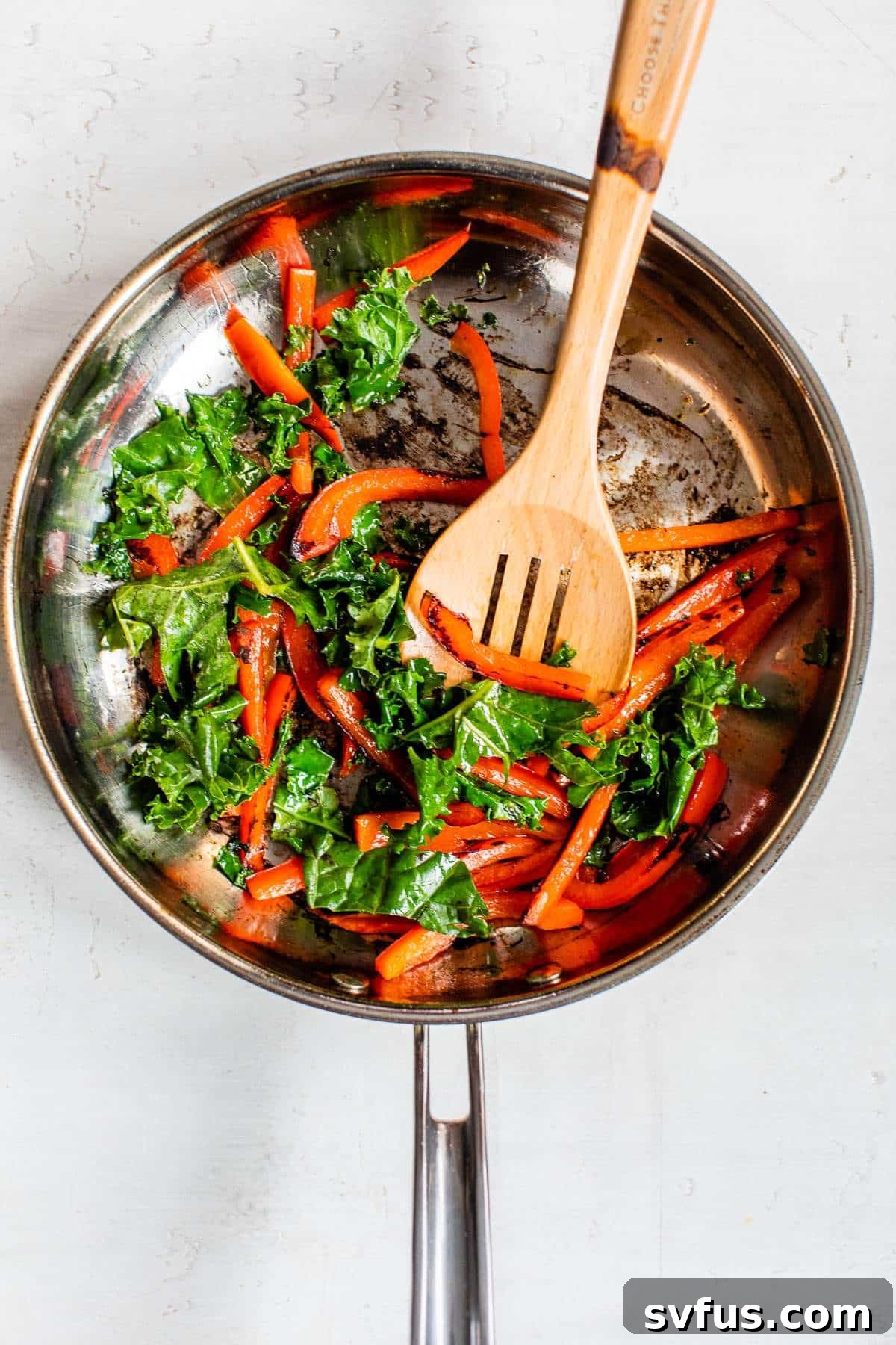 Cooked bell pepper slices and wilted kale in a skillet