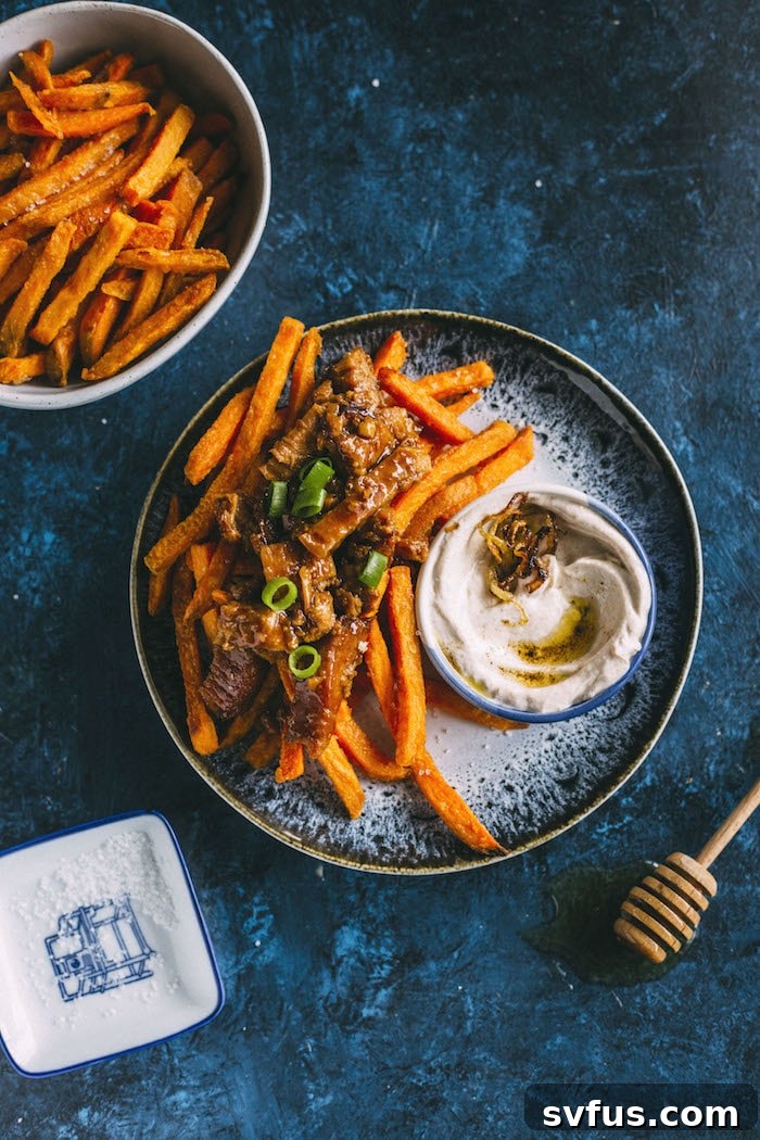 Overhead shot of a platter of loaded fries, showcasing the crispy sweet potatoes, rich pork, and vibrant green onion garnish.