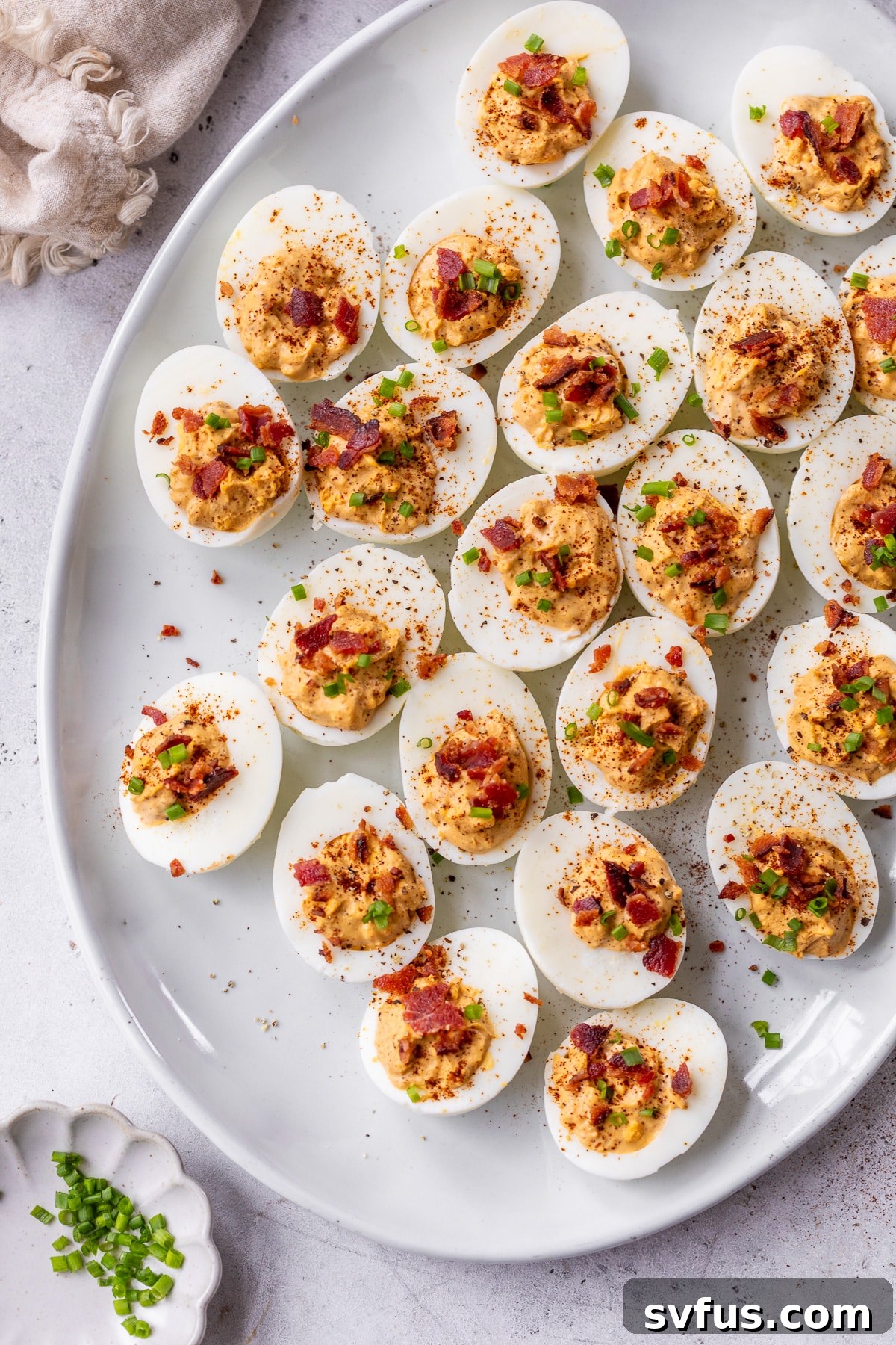 Overview of finished chipotle deviled eggs topped with chives arranged on a plate