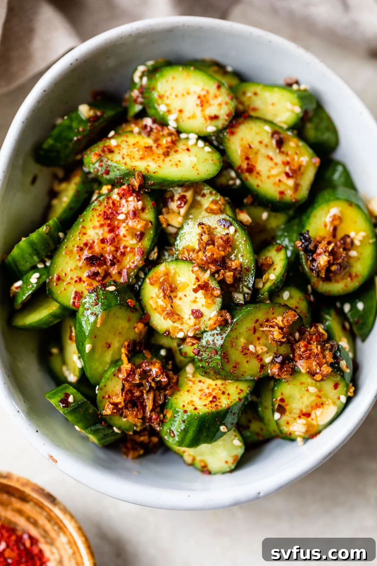 Sliced cucumbers in a bowl topped with chili flakes, ready to be served as a spicy cucumber salad