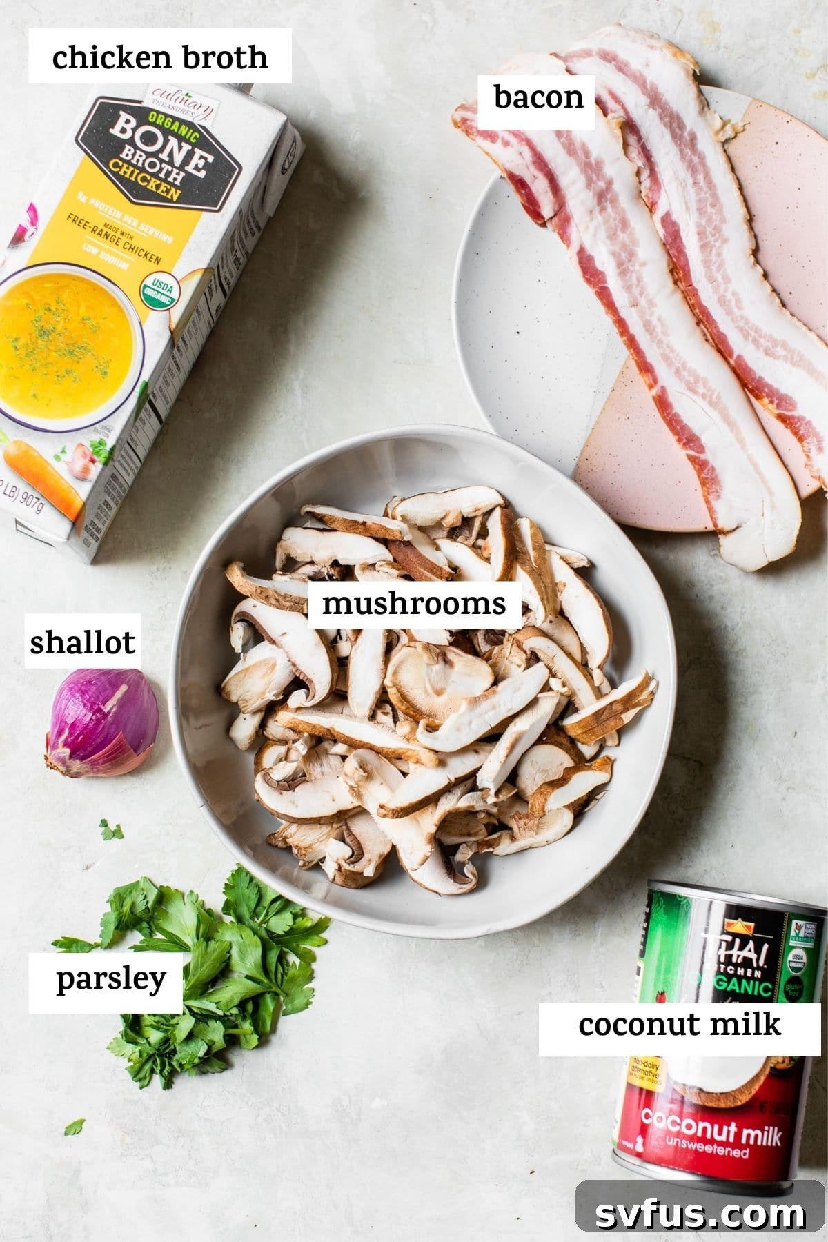 A vibrant flat lay of fresh ingredients for Whole30 mushroom soup, including various mushrooms, shallots, and coconut milk.