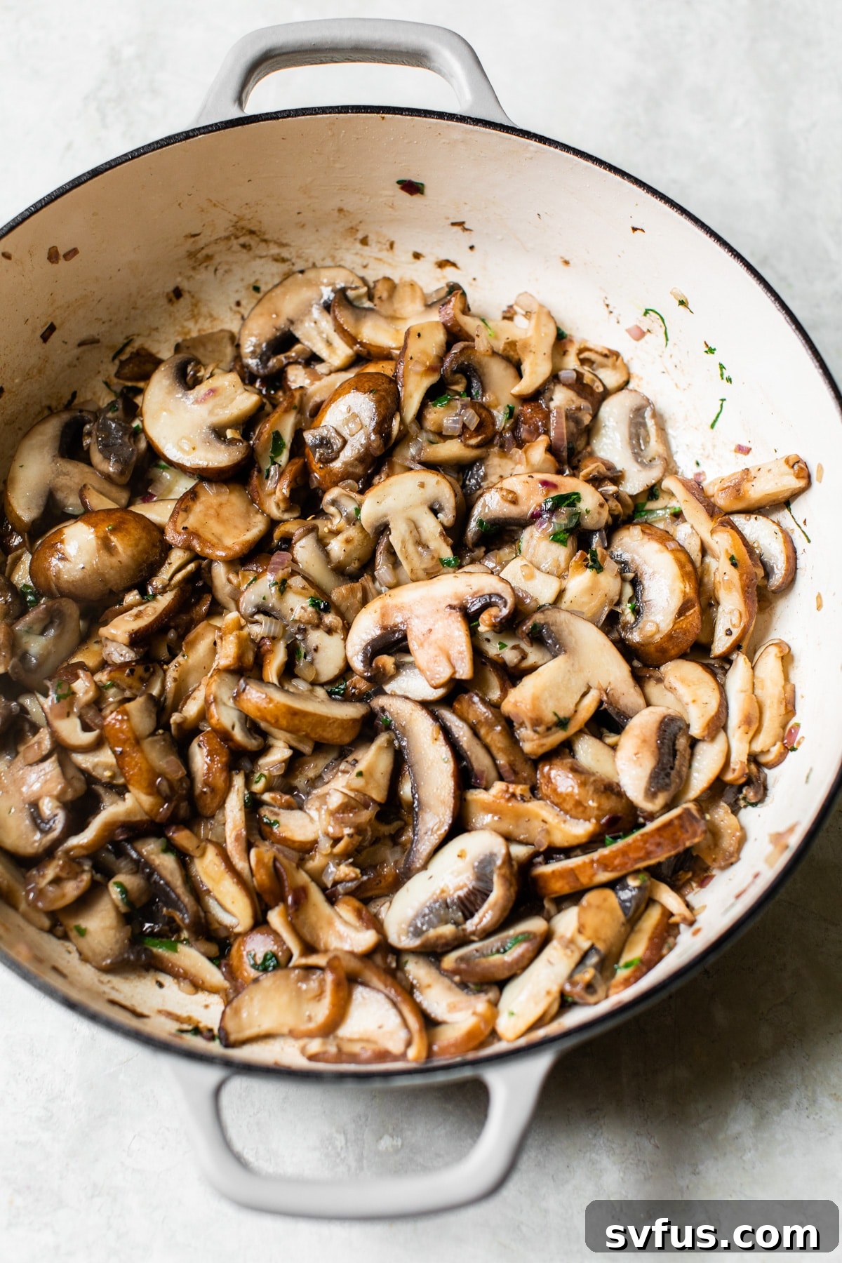 Sautéed mixed mushrooms cooking in a Dutch oven, ready for the next step of the soup preparation.