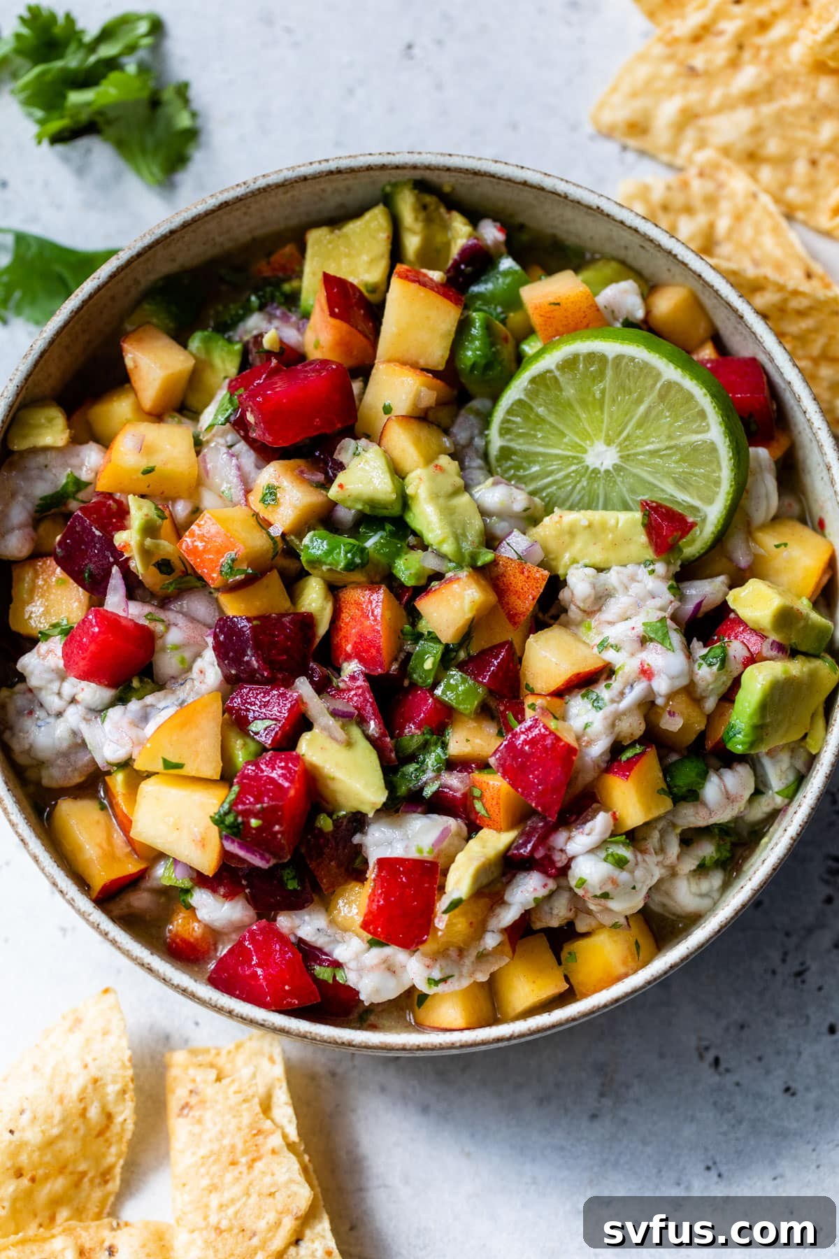 A beautifully presented bowl of Stone Fruit Ceviche, garnished with a lime wedge, ready to be served.