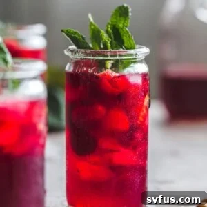 Pitcher of Raspberry Hibiscus Iced Tea with ice, raspberries, and mint.