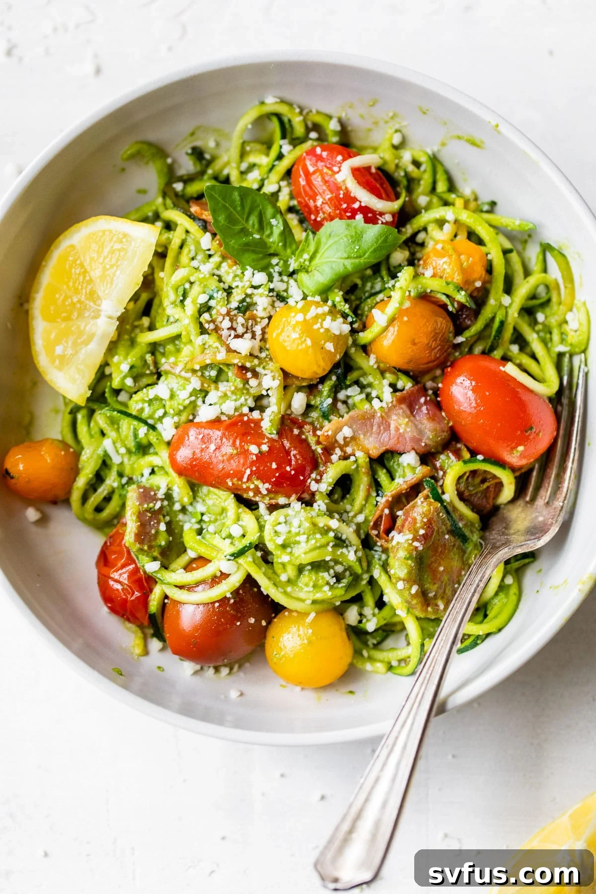 zucchini noodles in a bowl with tomatoes and bacon, ready to be enjoyed as a summer meal