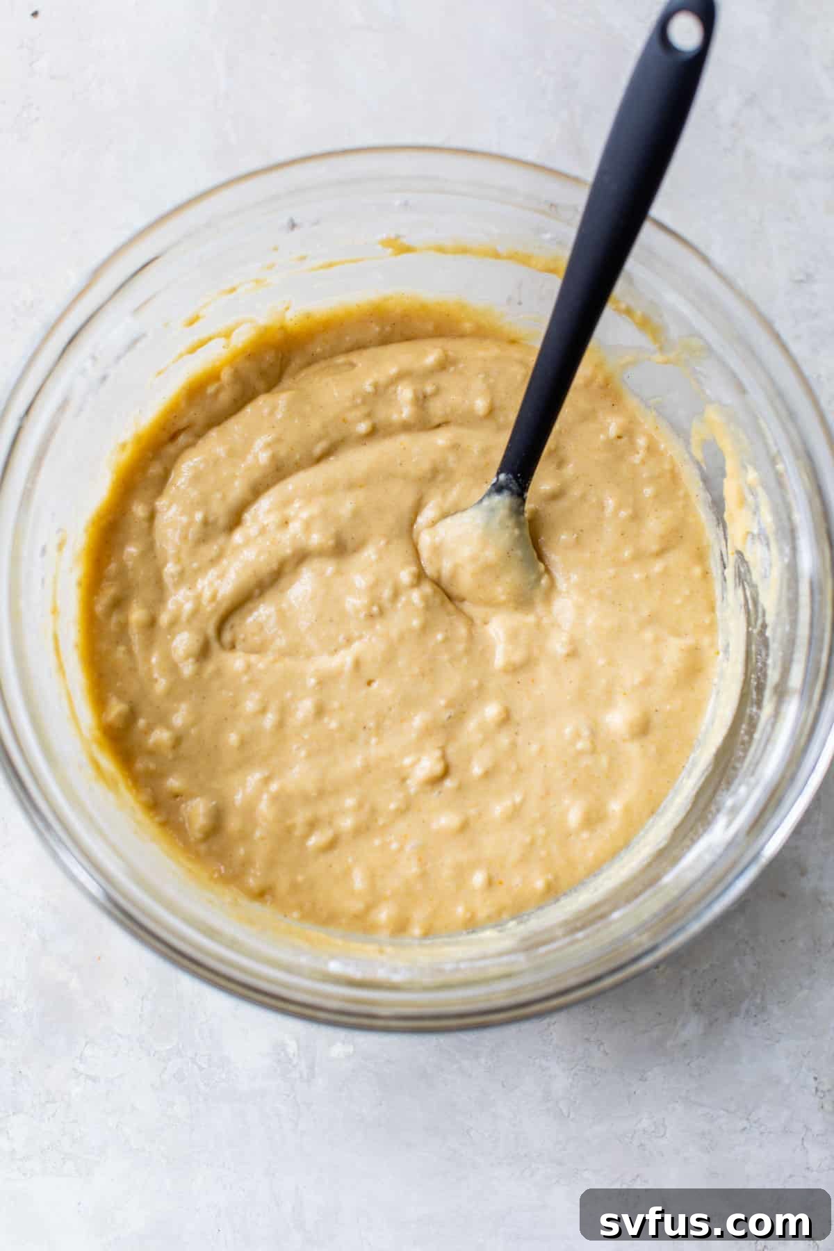cake batter in a large glass bowl with a rubber spatula