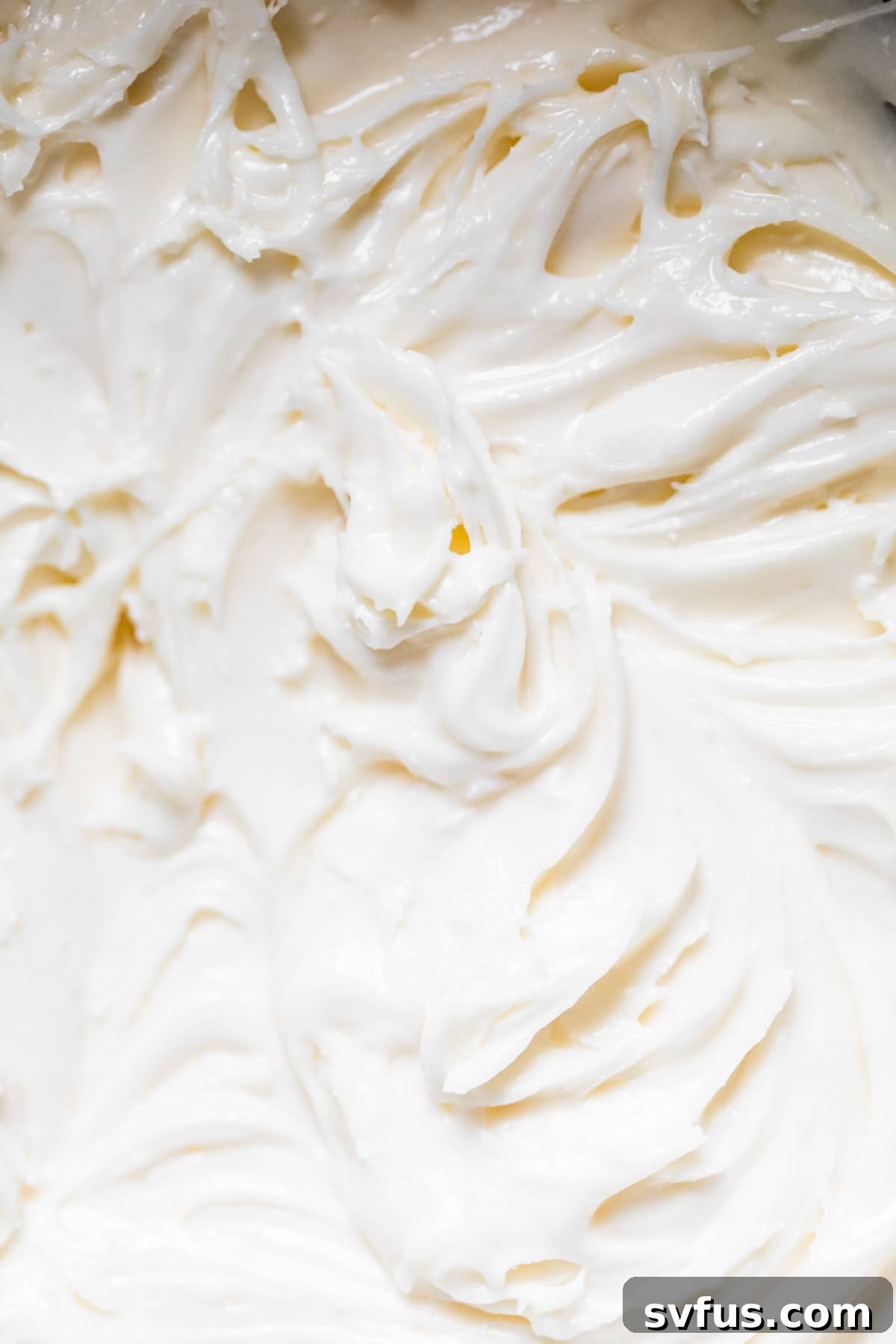 Close-up shot of creamy, smooth buttercream icing, perfectly whipped and ready to be spread onto delectable cupcakes.