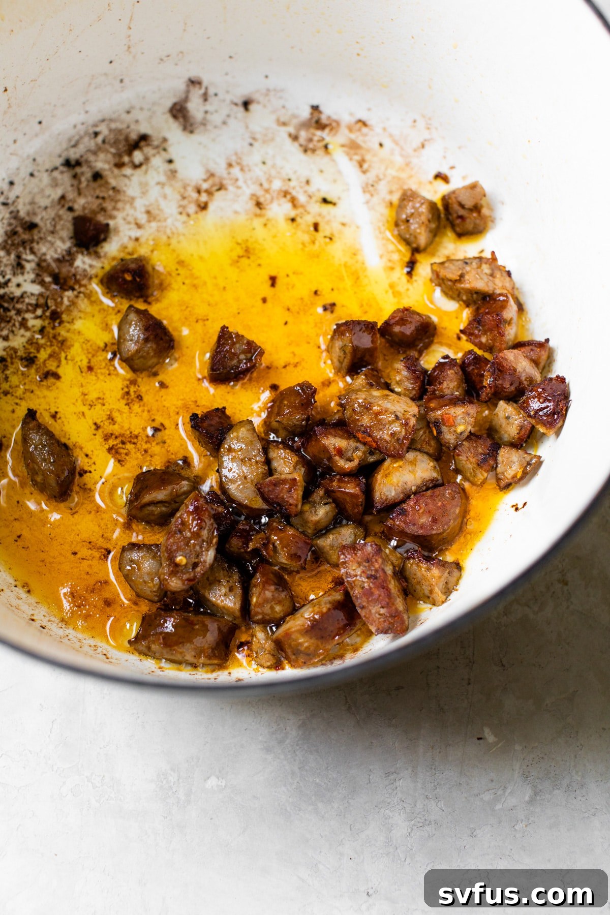 Sizzling chorizo cooking in a Dutch oven, releasing its fragrant oils