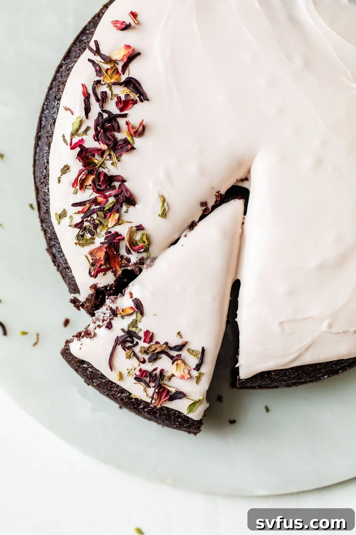 Round chocolate cake topped with a beautiful pink hibiscus icing, ready to be sliced.