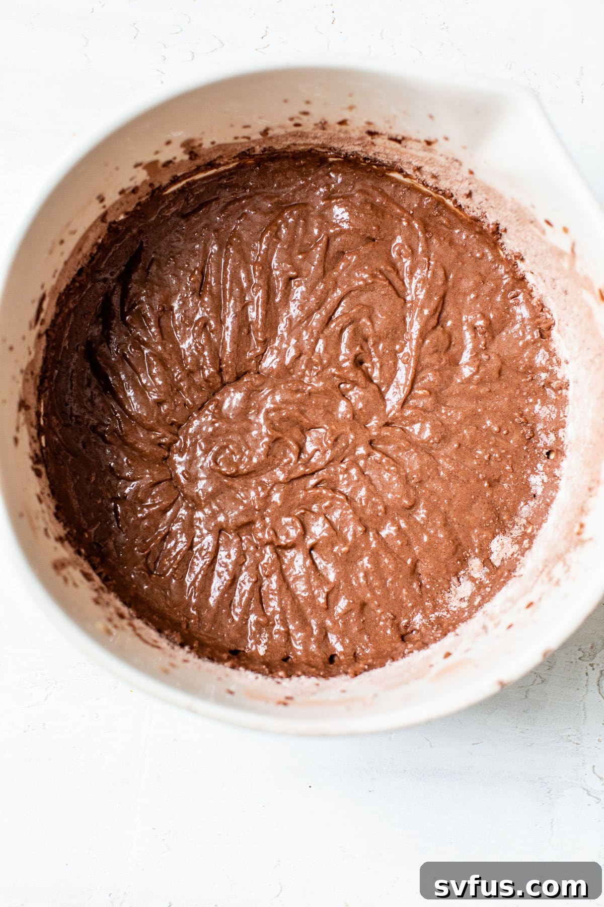 Smooth chocolate cake batter ready for baking in a bowl.