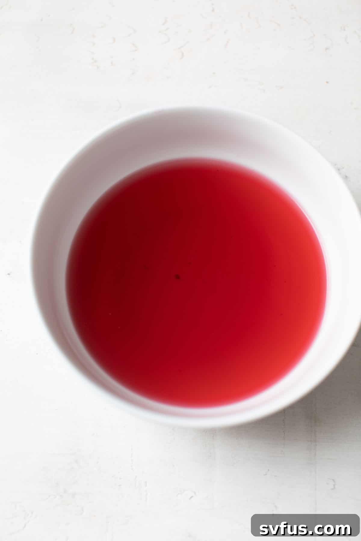 Freshly brewed hibiscus tea in a bowl, ready to be used for the icing.