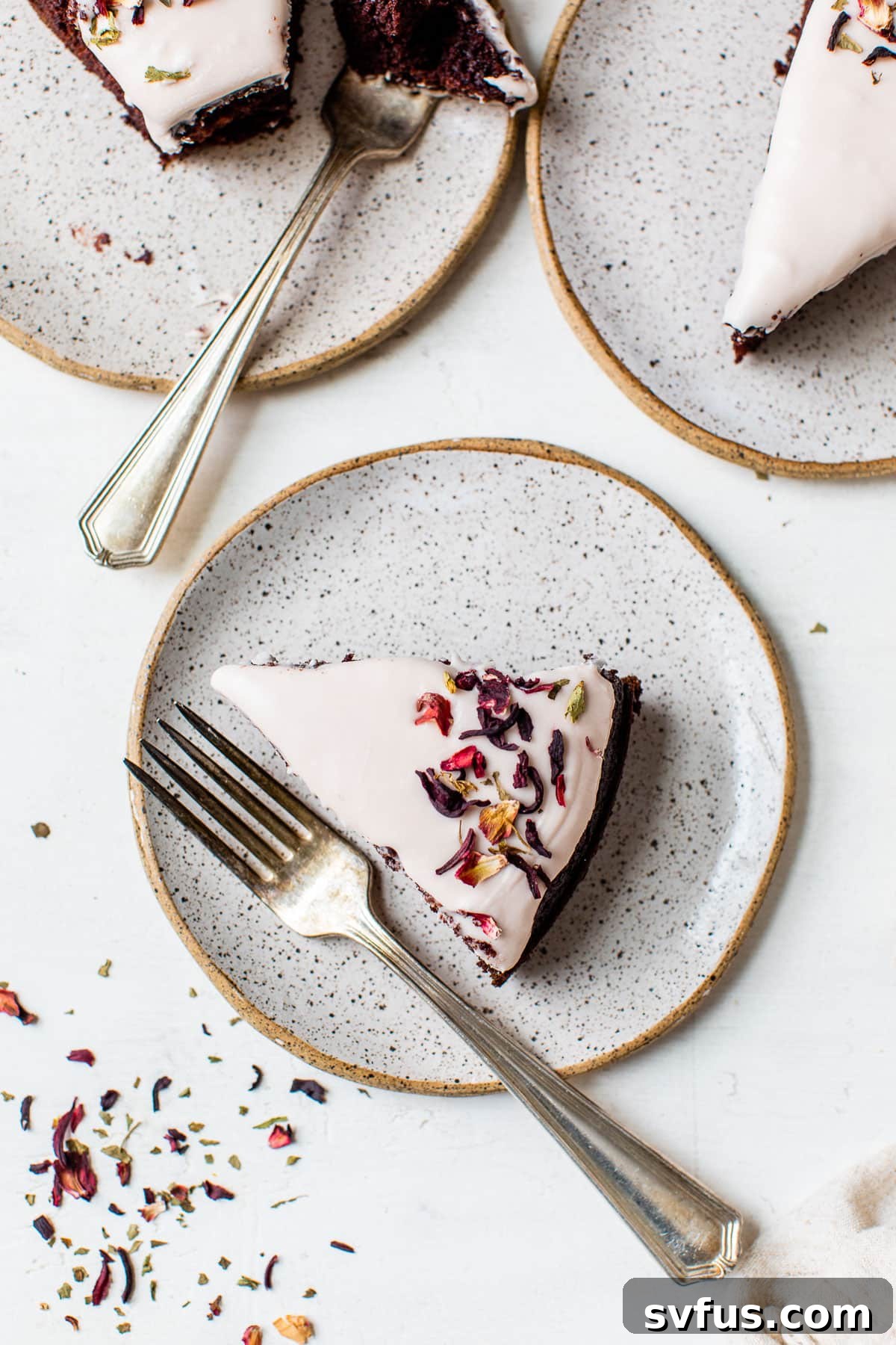 Individual slices of chocolate cake topped with pink icing arranged on small dessert plates.